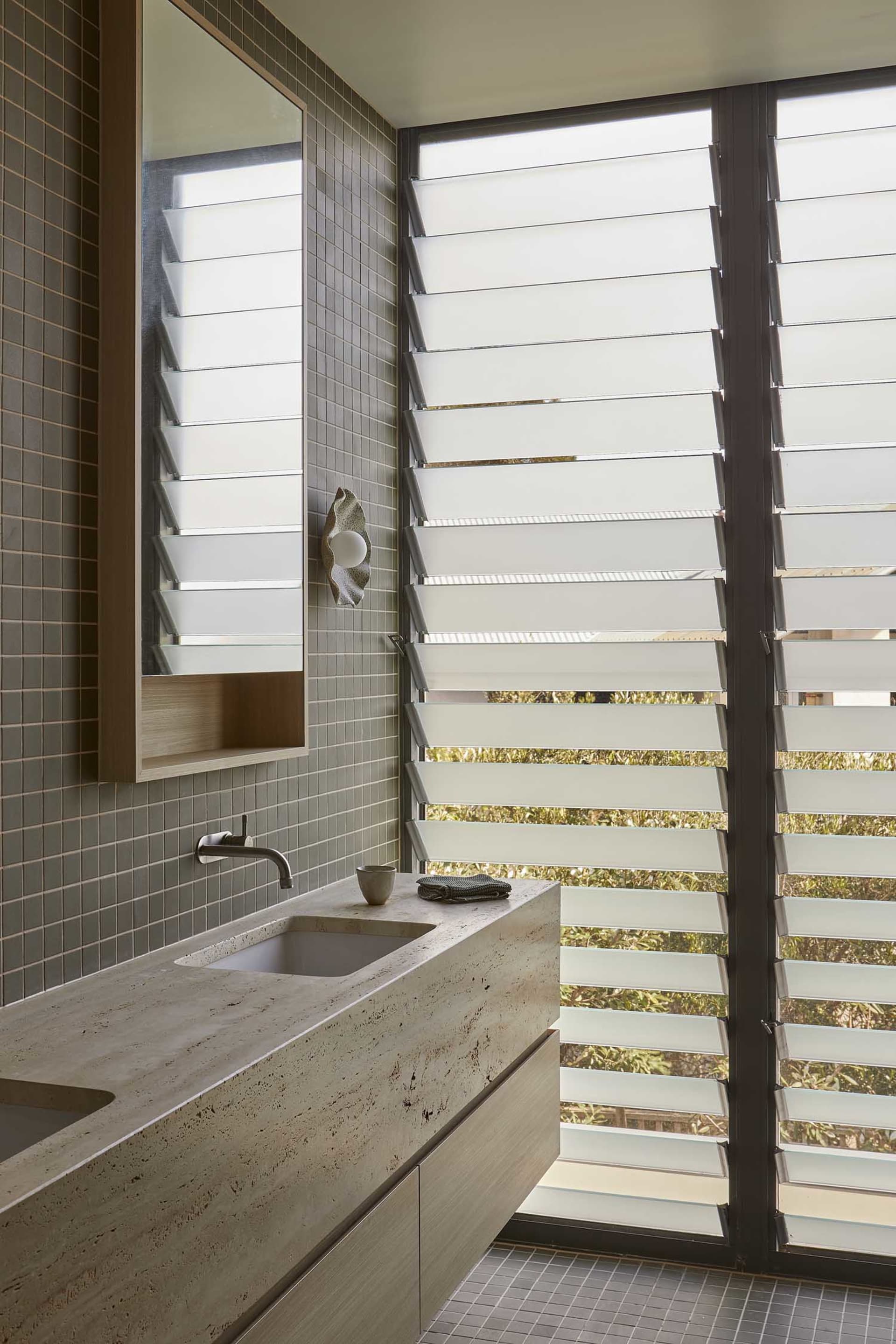 Bathroom with a tiled floor, wooden countertop, metal sink, and a window allowing natural light to enter