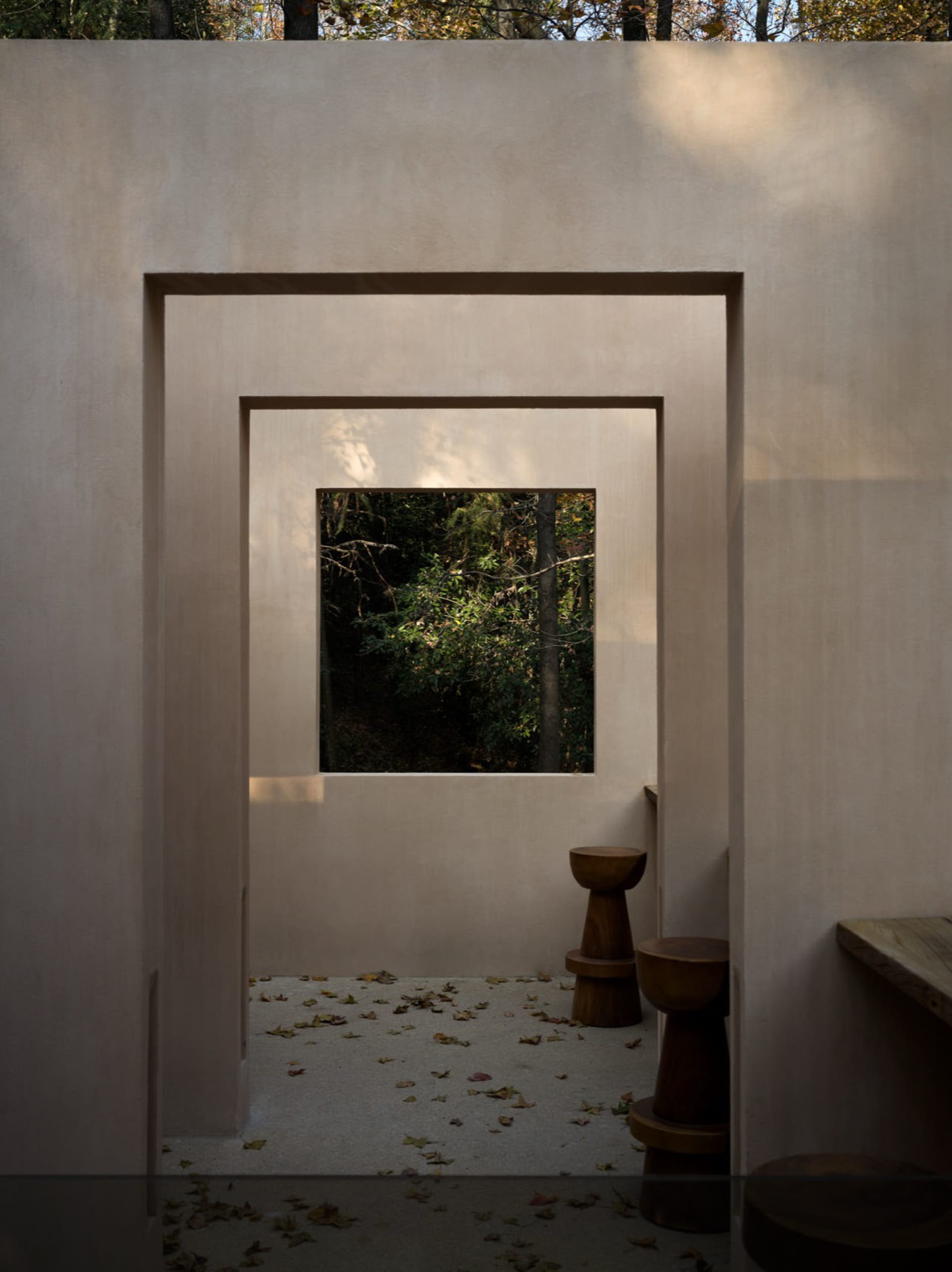 Dimly lit bathroom with concrete walls, two toilets, and a window allowing natural light