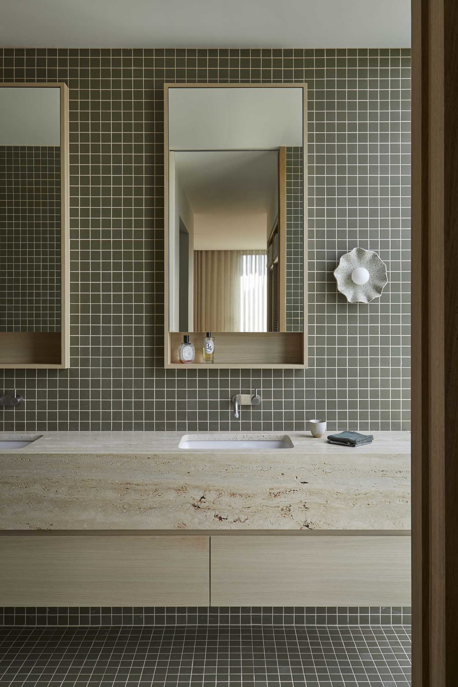 Bathroom with a sink, mirror, and tile wall in a dimly lit space