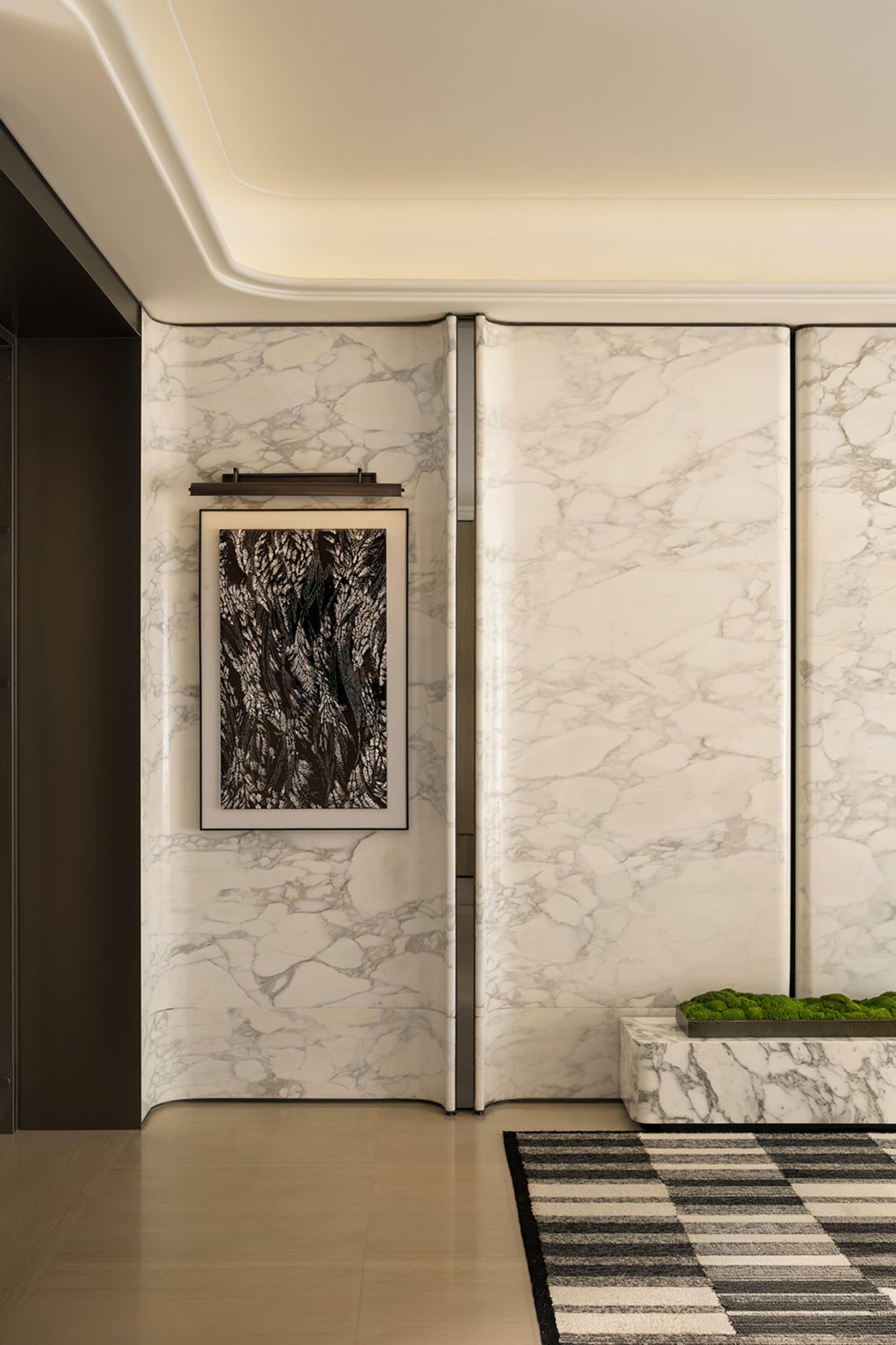 Dimly lit bathroom with a white marble wall, a door, and a toilet, creating a cozy and intimate atmosphere