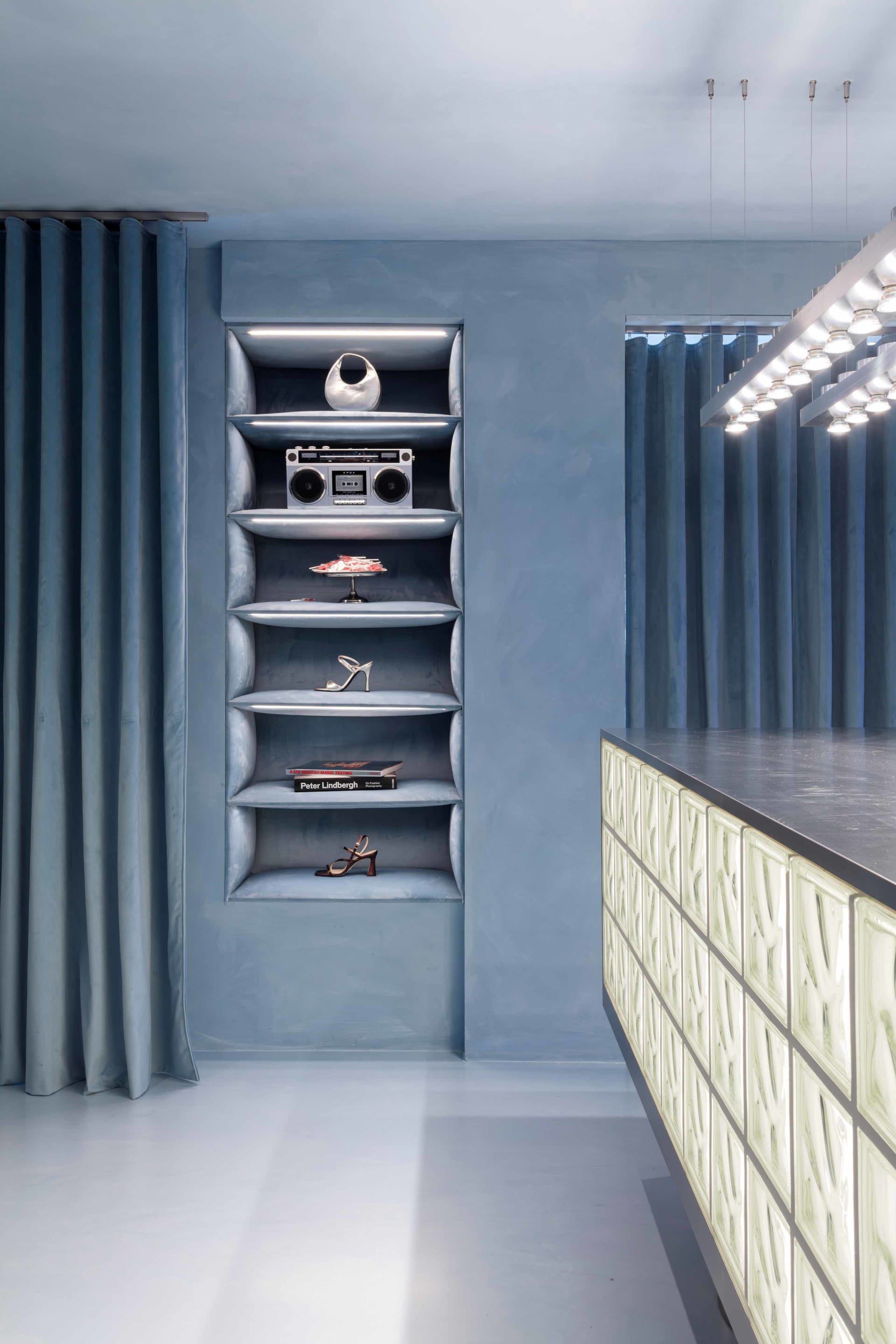 A modern living space with a blue accent wall, a shelf with various items, and a boombox on top of it
