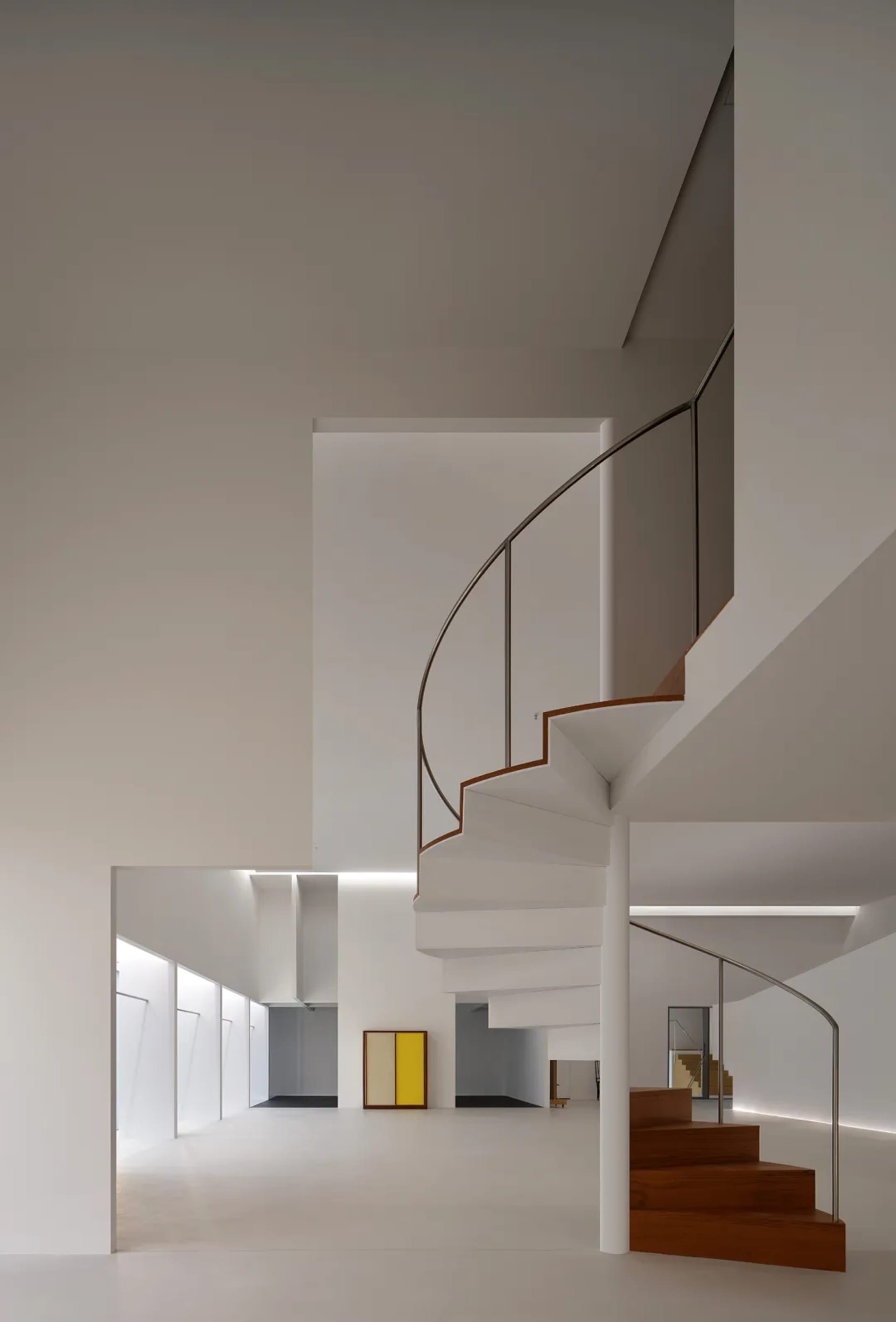 A wooden staircase with a metal railing in a bright and inviting hallway with a door at the bottom of the stairs