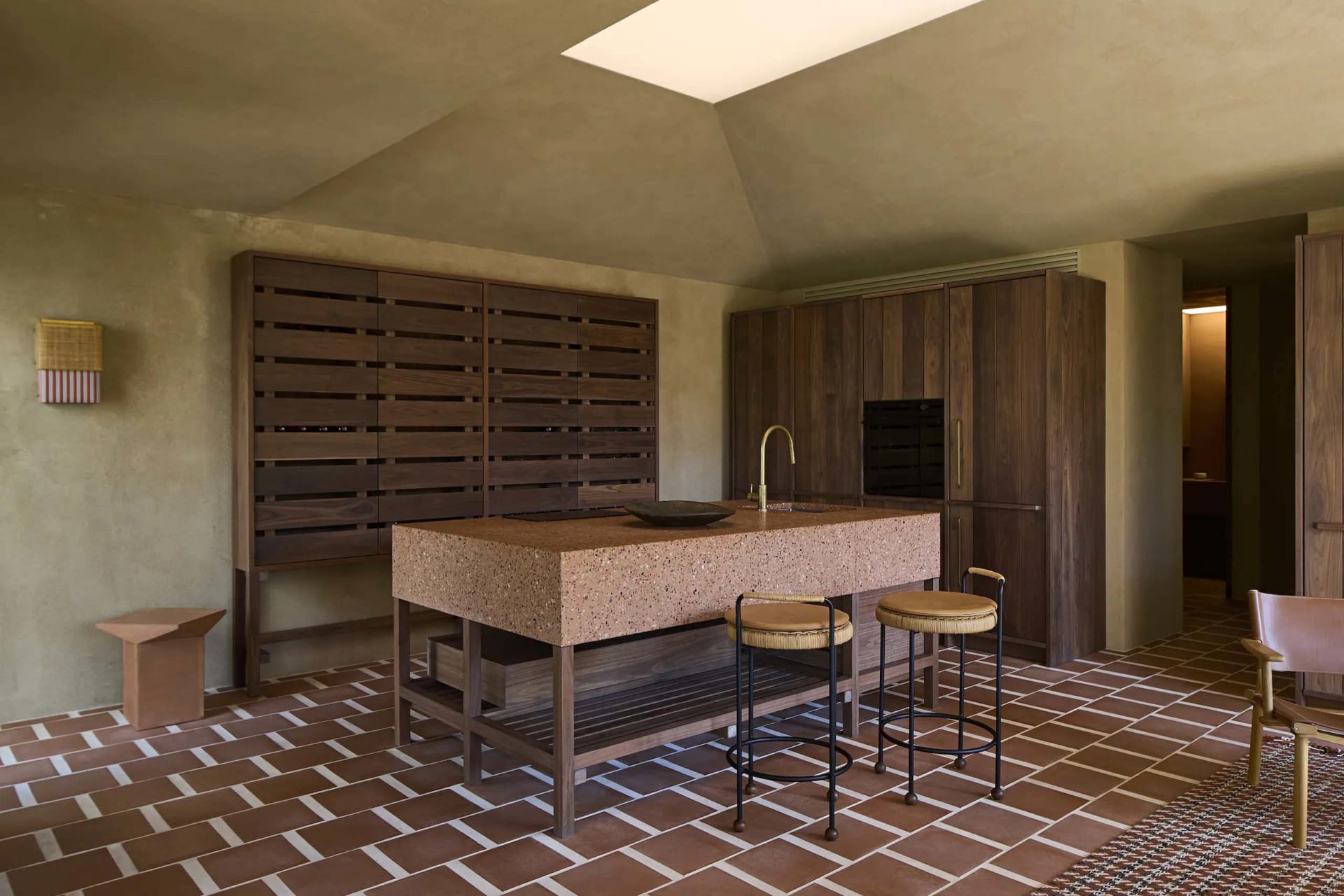 A modern kitchen with a wooden counter, tile floor, and white refrigerator, lit by natural sunlight through a window