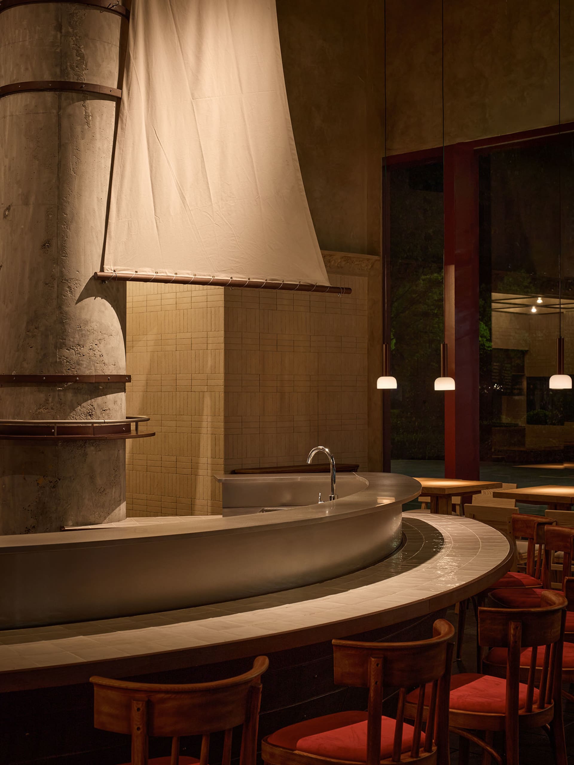 Cozy modern restaurant interior with a bar, wooden and stone elements, and a unique sail-like structure