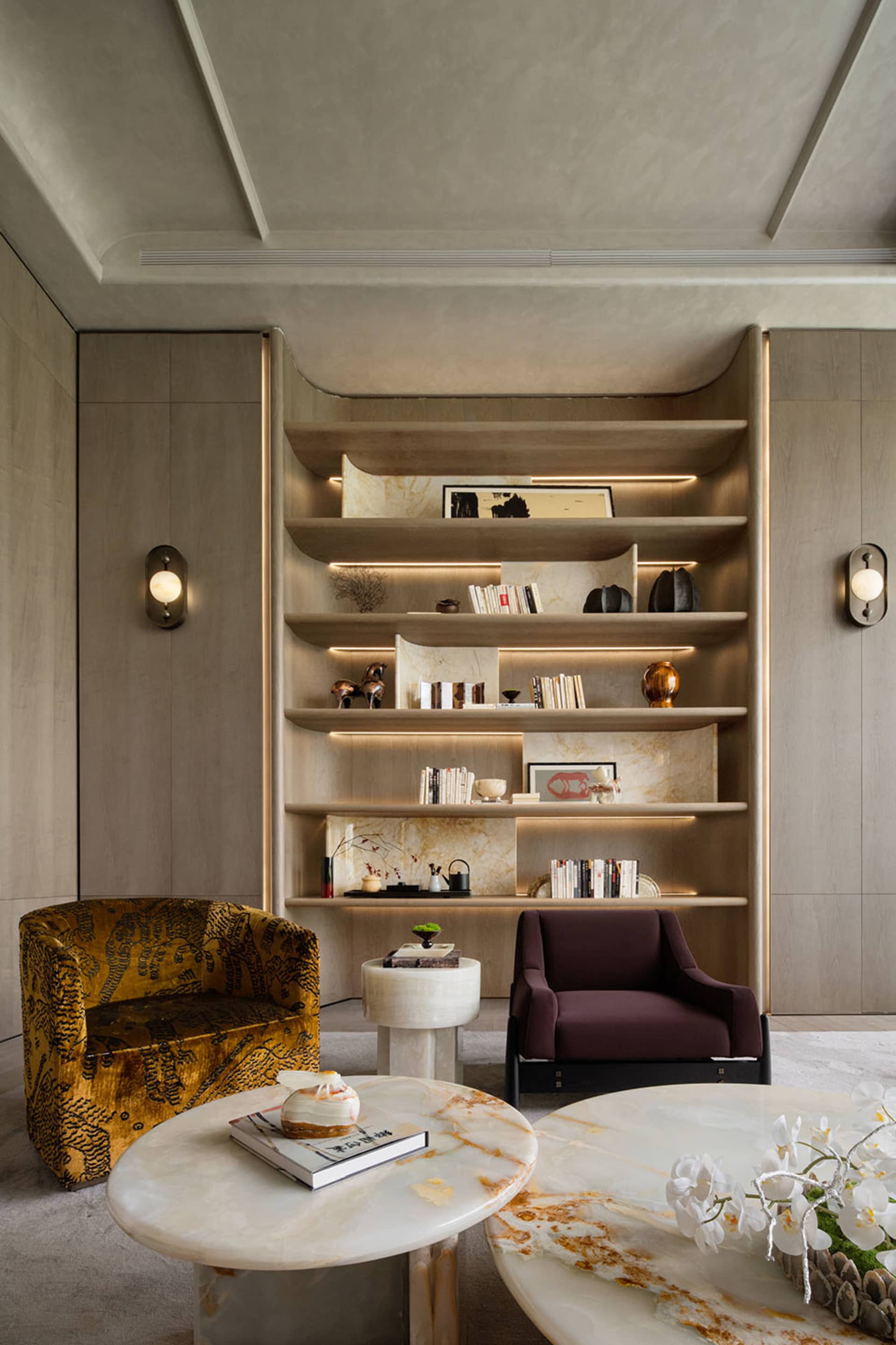 Cozy living room with a couch, chair, and bookshelf, decorated with vases and featuring warm wood and fabric materials