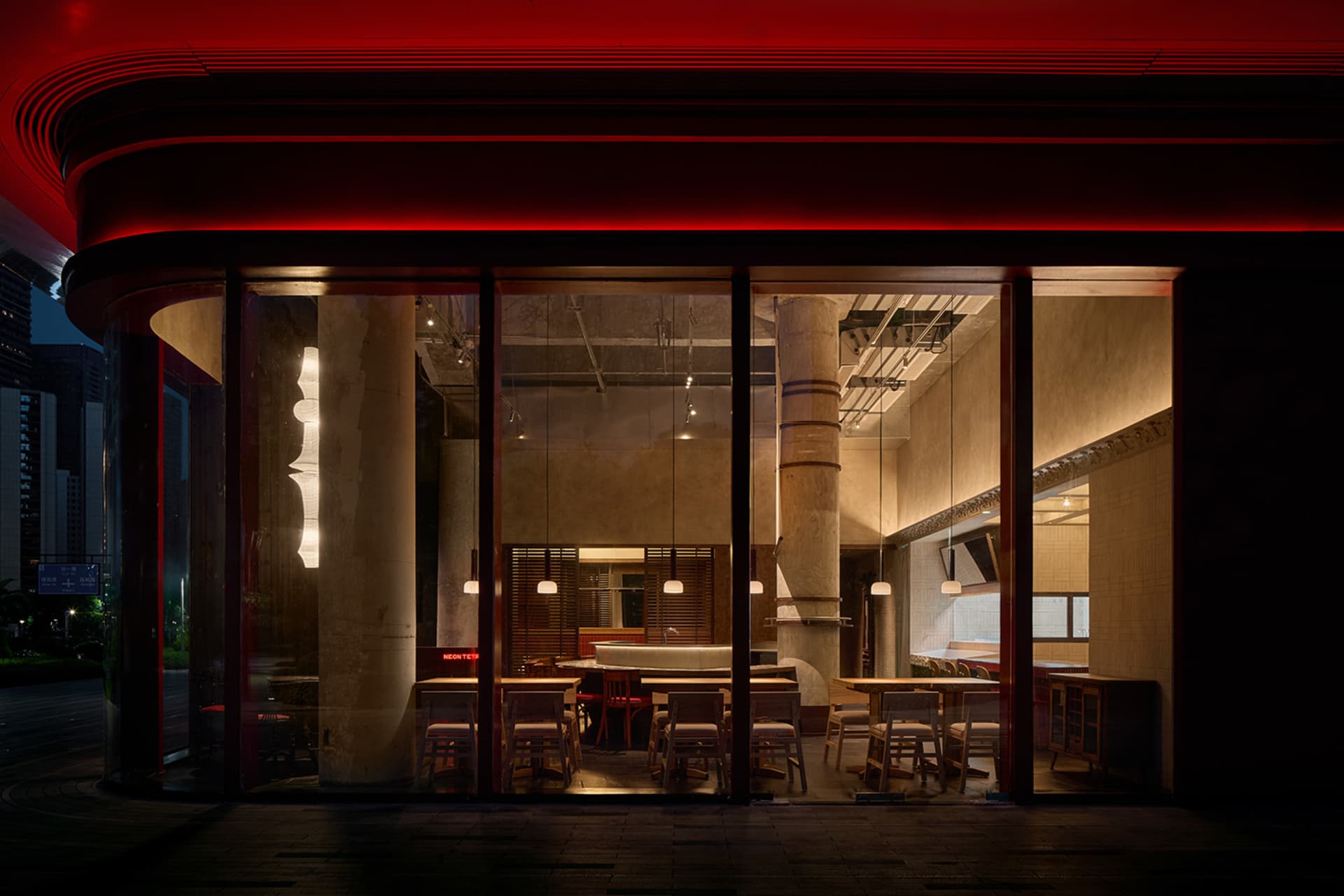 A modern restaurant interior with dining tables, chairs, and benches in a neutral color palette, with warm and soft lighting