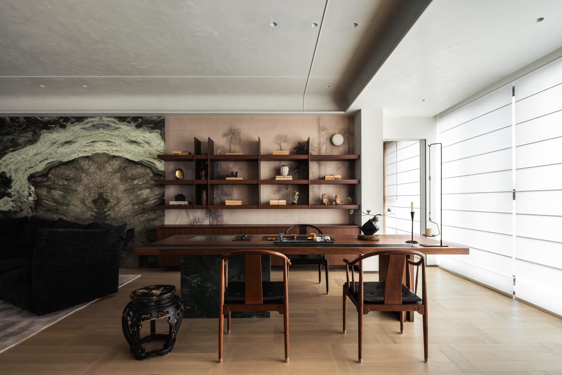 Modern dining room featuring a solid walnut table, matching Chinese-style armchairs, dark green marble base, and a dramatic large-format marble art wall with built-in walnut shelving.