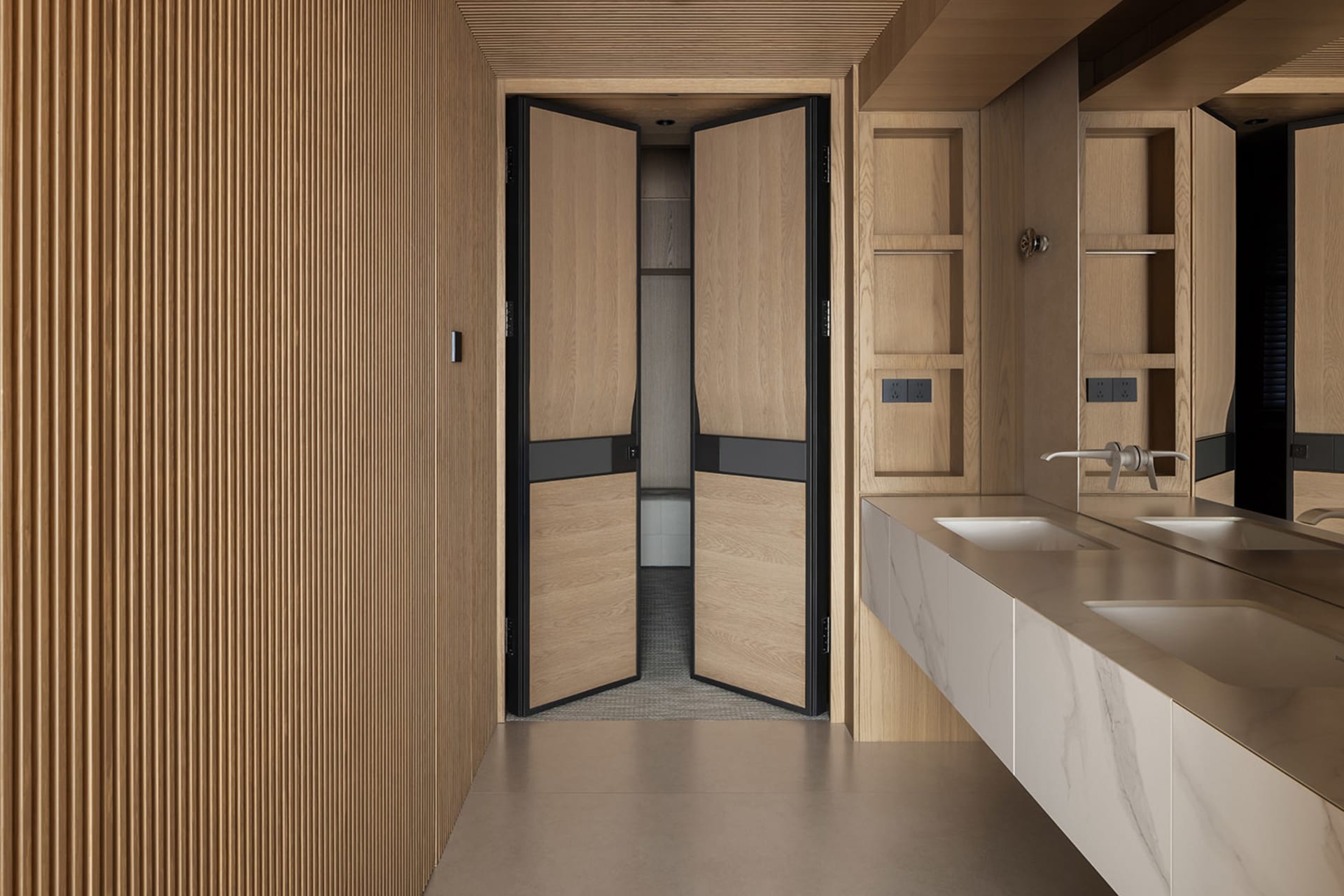 Modern minimalist bathroom interior with double white marble sinks, oak vanity, large mirror, and a prominent light oak fluted wood wall panel on the left.