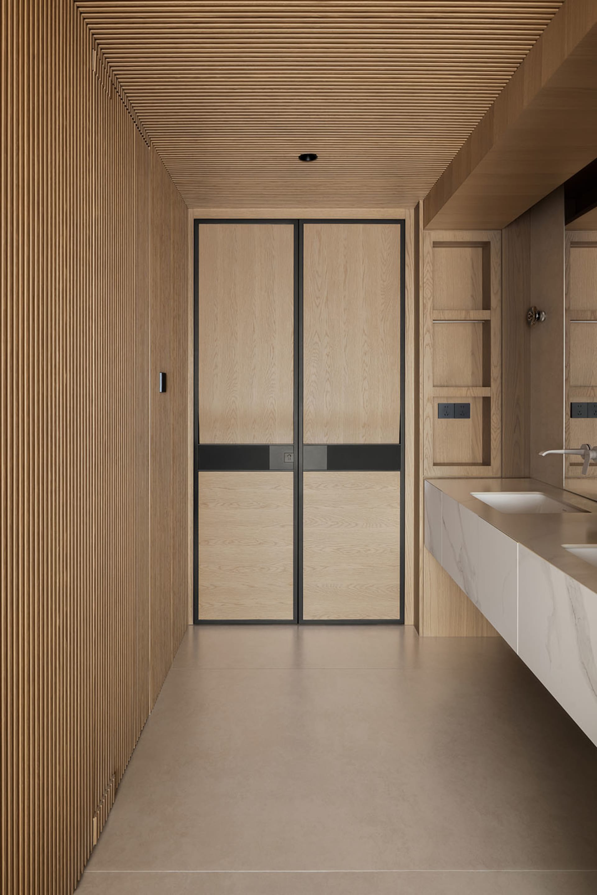 Modern minimalist bathroom with light oak fluted wall panels, double-door oak cabinet with black metal frame, and a white marble floating vanity under a large mirror.