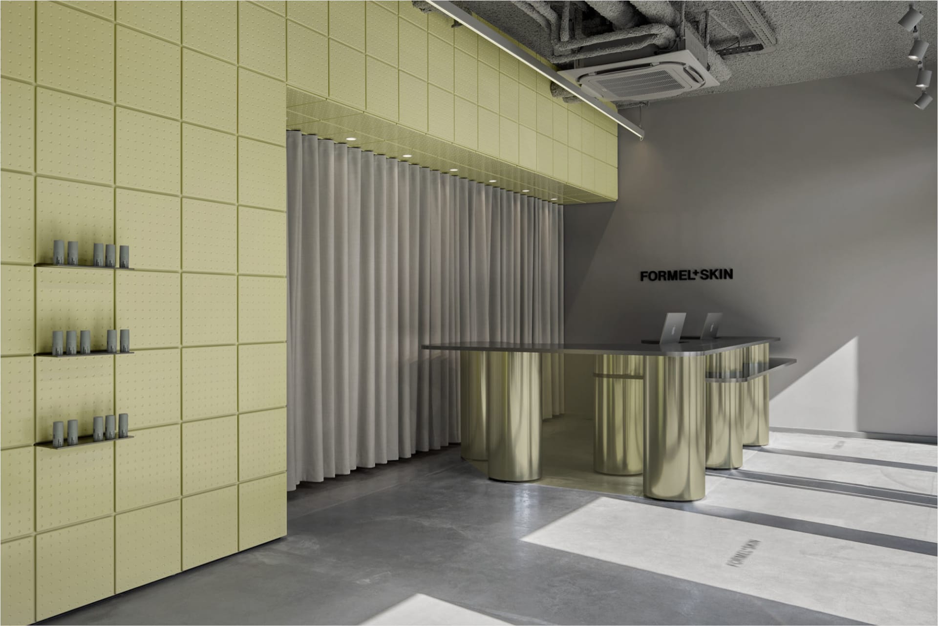 Modern retail reception area with curved brushed-metal desk, lime green padded acoustic wall panels, and grey curtain backdrop.