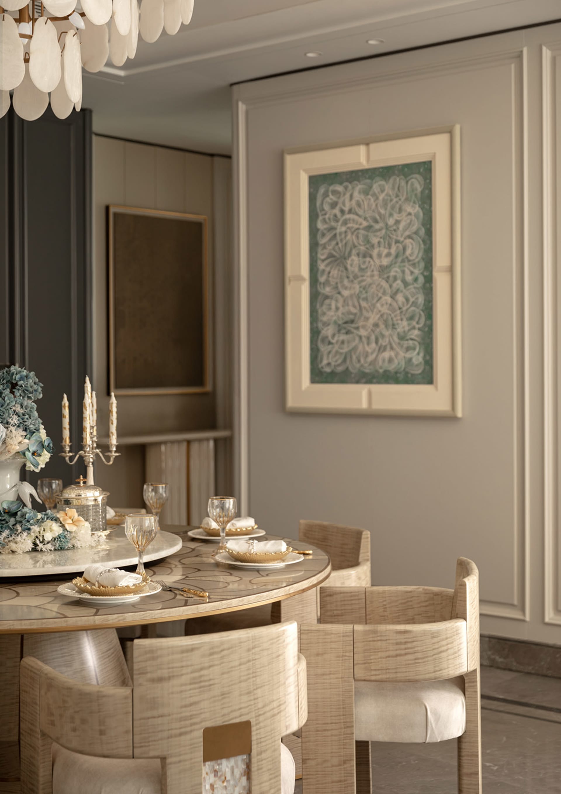 Elegant dining room with round marble dining table, light oak upholstered chairs, shell chandelier, and large floral artwork on a paneled wall.