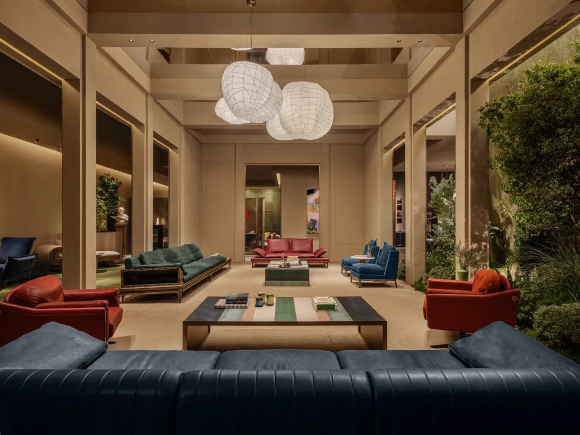 Modern luxury hotel lobby lounge with colorful sofas in red, teal, and navy, large spherical woven pendant lights, and integrated indoor greenery.