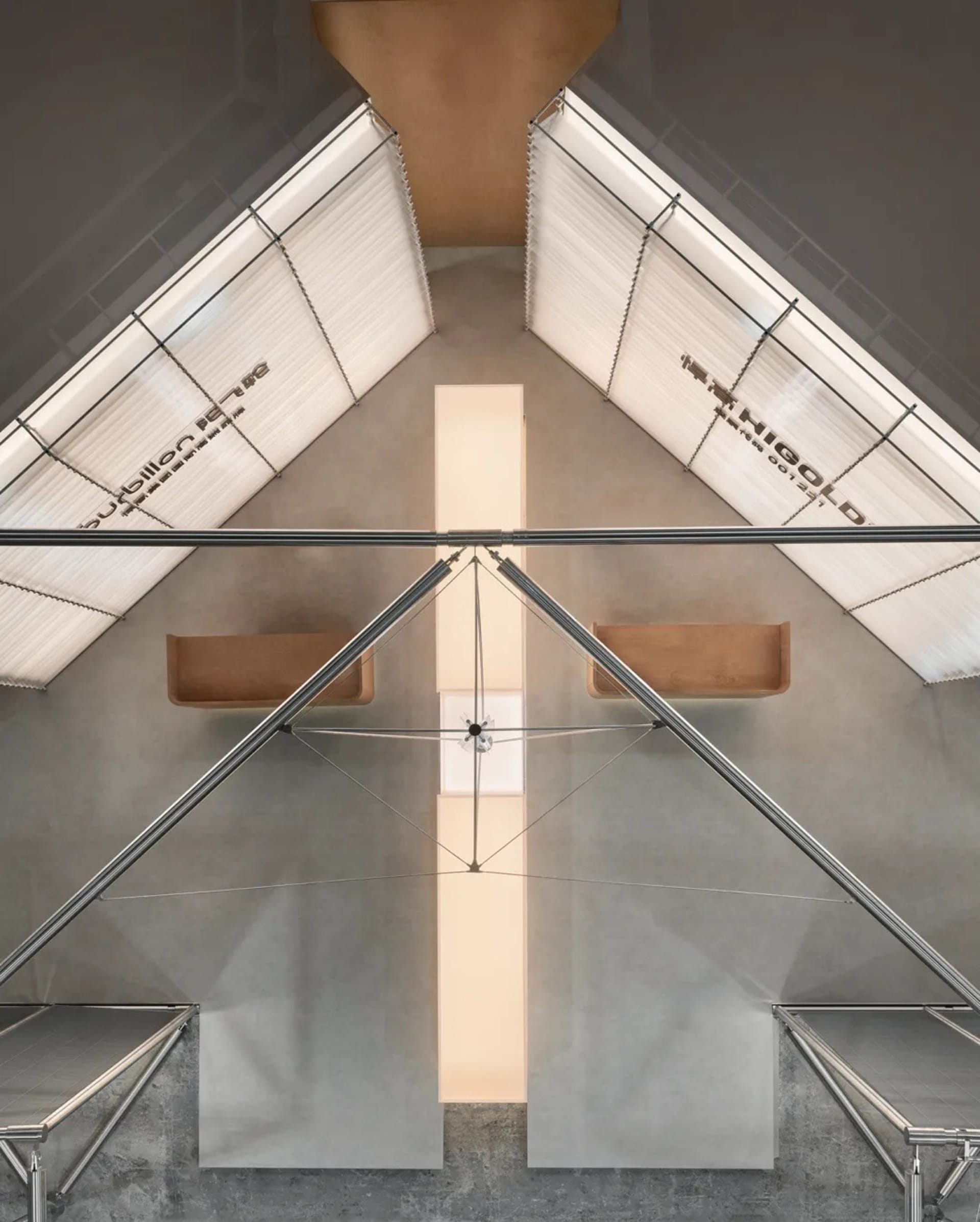 Top-down architectural view of a modern concrete atrium with two suspended brown leather benches, steel cable system, and large angled skylights with white blinds.