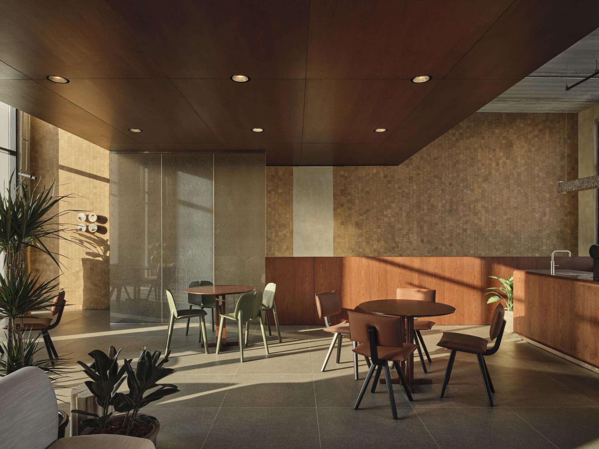 Modern cafe interior with round wooden tables, mixed green and brown leather chairs, wood-paneled walls and ceiling, and potted plants under natural sunlight.