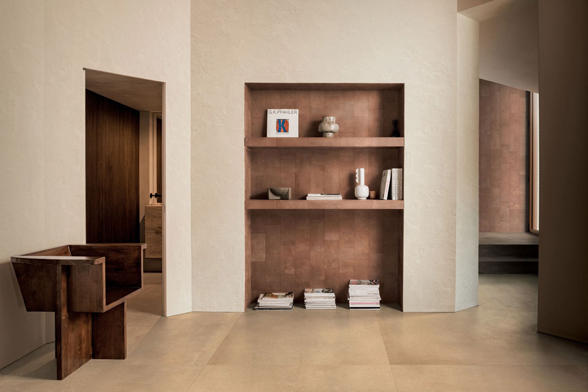 Modern minimalist entryway featuring a built-in terracotta tiled shelving unit, dark walnut sculptural console table, and neatly arranged books and ceramics.