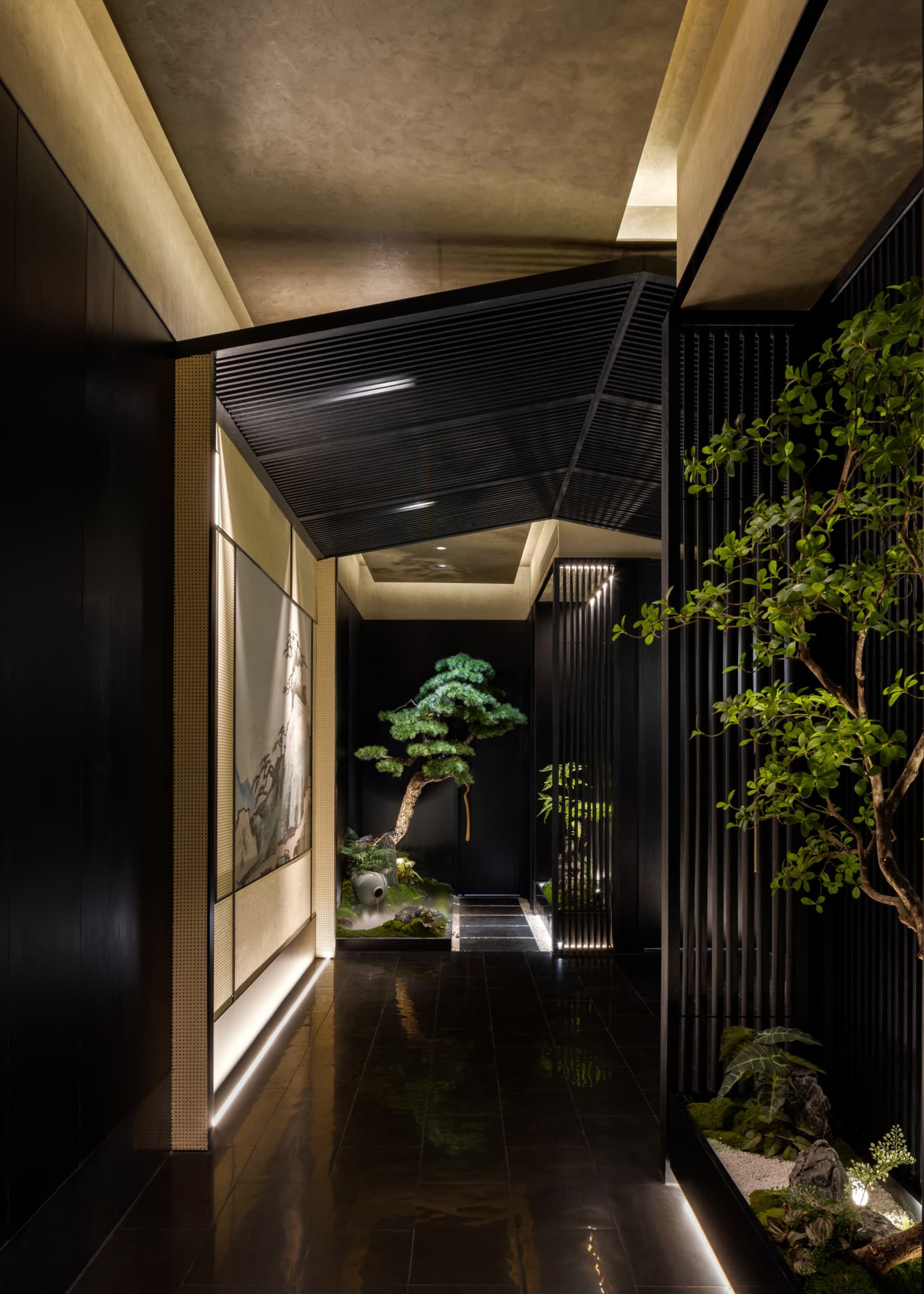 Modern Japanese-style hallway featuring dark wood paneling, linear LED lighting, a large bonsai tree, and a miniature zen garden with rocks and moss.