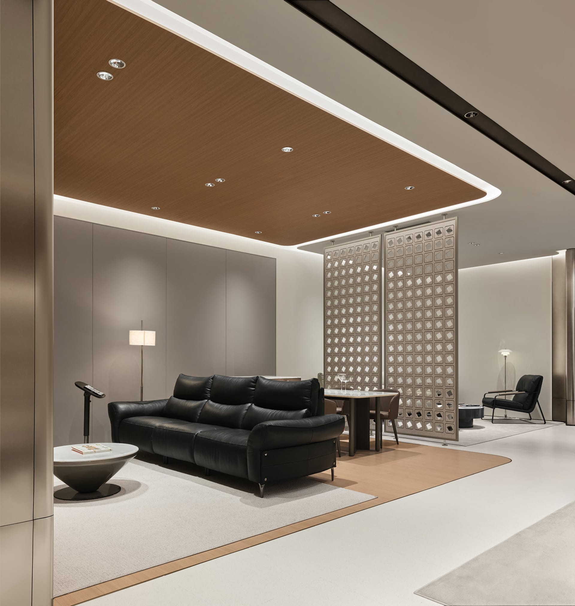 Modern luxury lounge with black leather sofa, curved wood ceiling with recessed lighting, decorative lattice room divider, and neutral-toned walls.