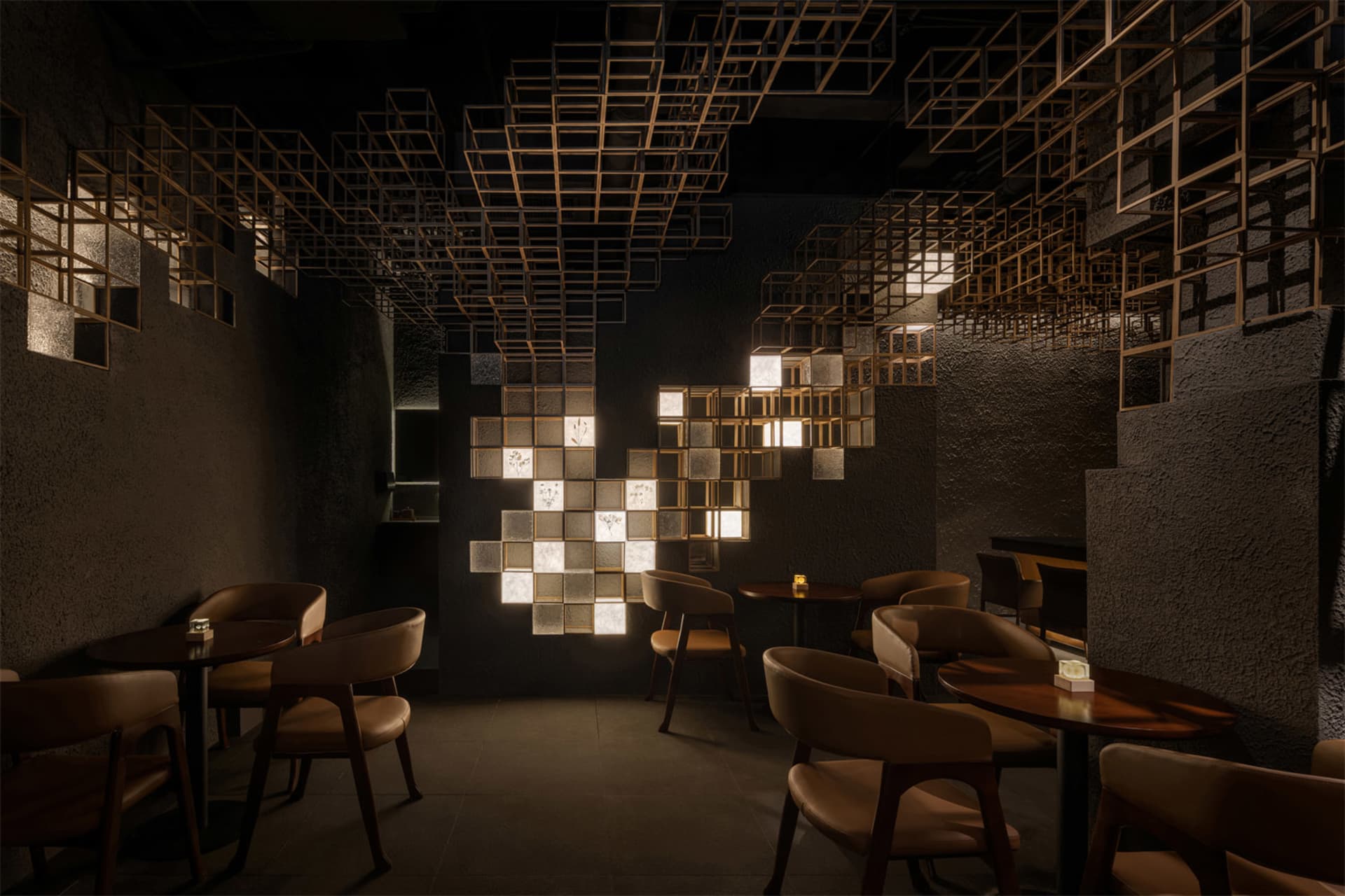 Modern restaurant interior featuring a large geometric light installation made of illuminated cubes, dark textured plaster walls, and warm brown leather dining chairs arranged around round wooden tables.