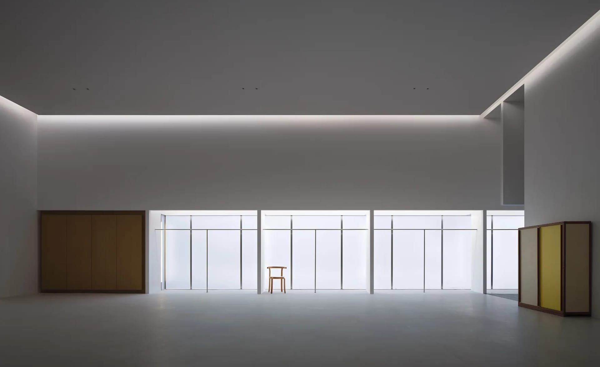 Modern minimalist white staircase featuring a tall vertical window, floating wooden storage cabinet, and a two-tone wooden box with yellow interior on the floor.