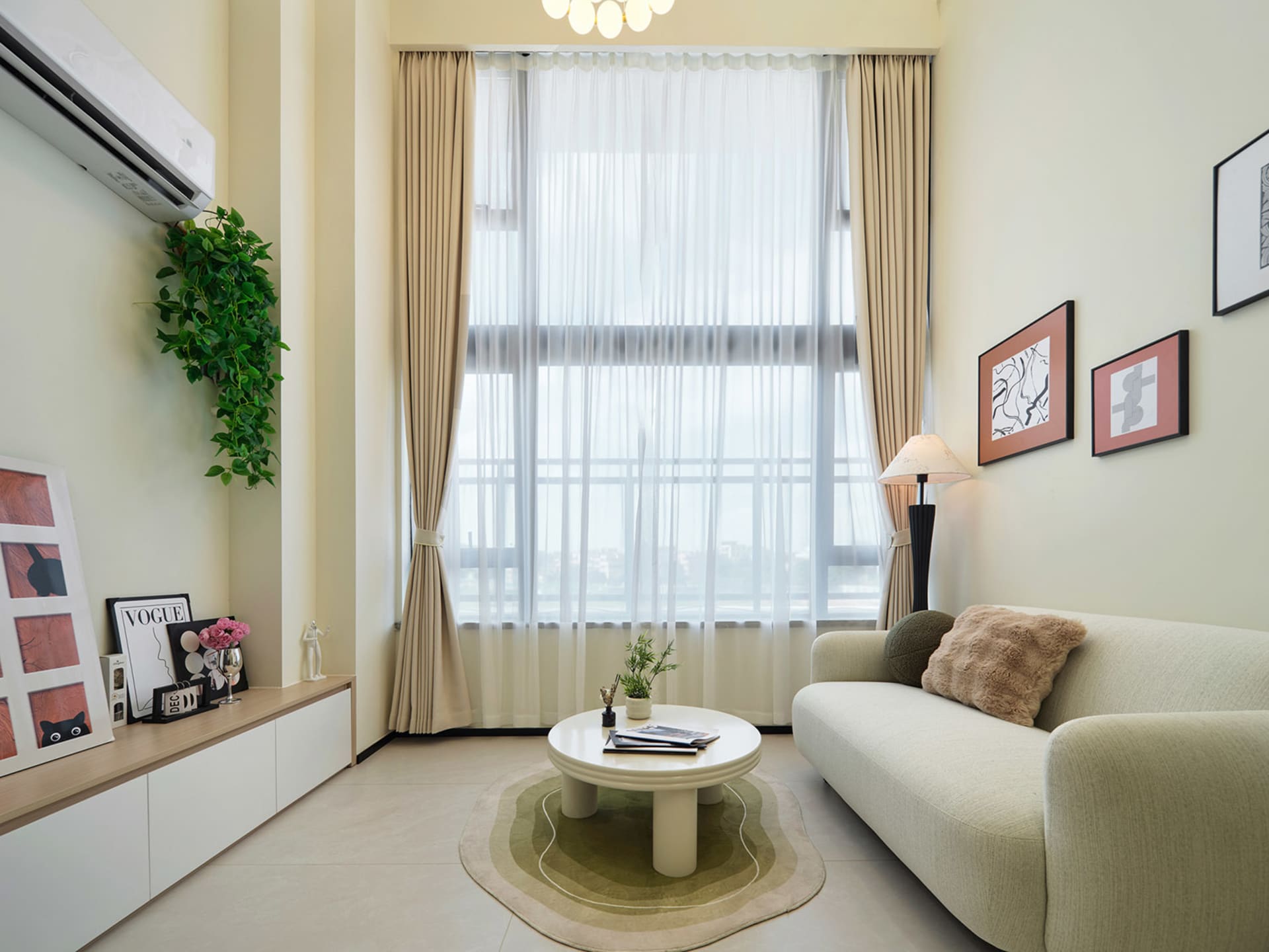 Modern minimalist living room with a sage green boucle sofa, curved white coffee table on a green rug, large window with sheer curtains, and built-in low cabinet displaying art and plants.
