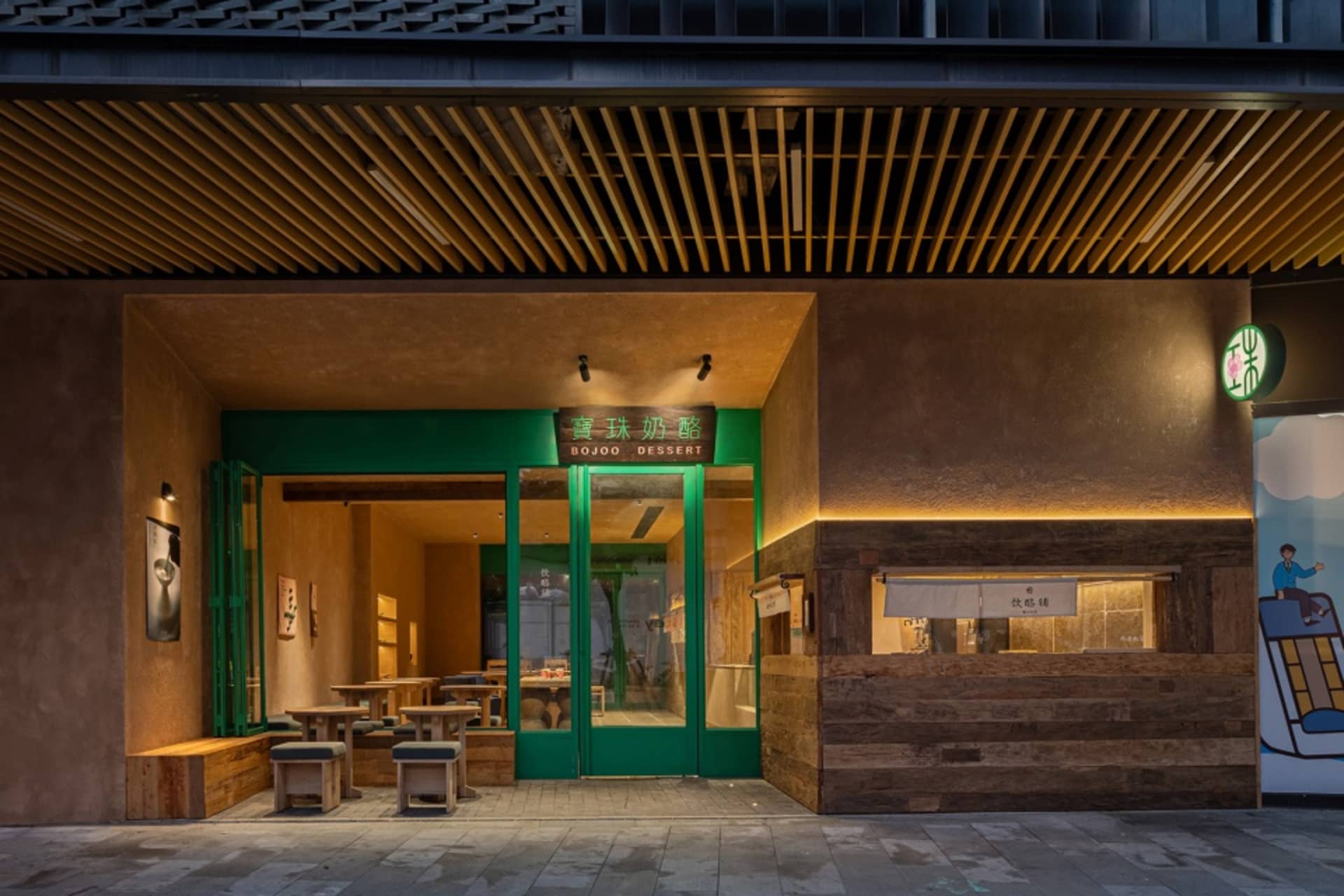 Night view of a modern dessert shop entrance with green doors, wooden counter, concrete walls and warm lighting in Taiwan.