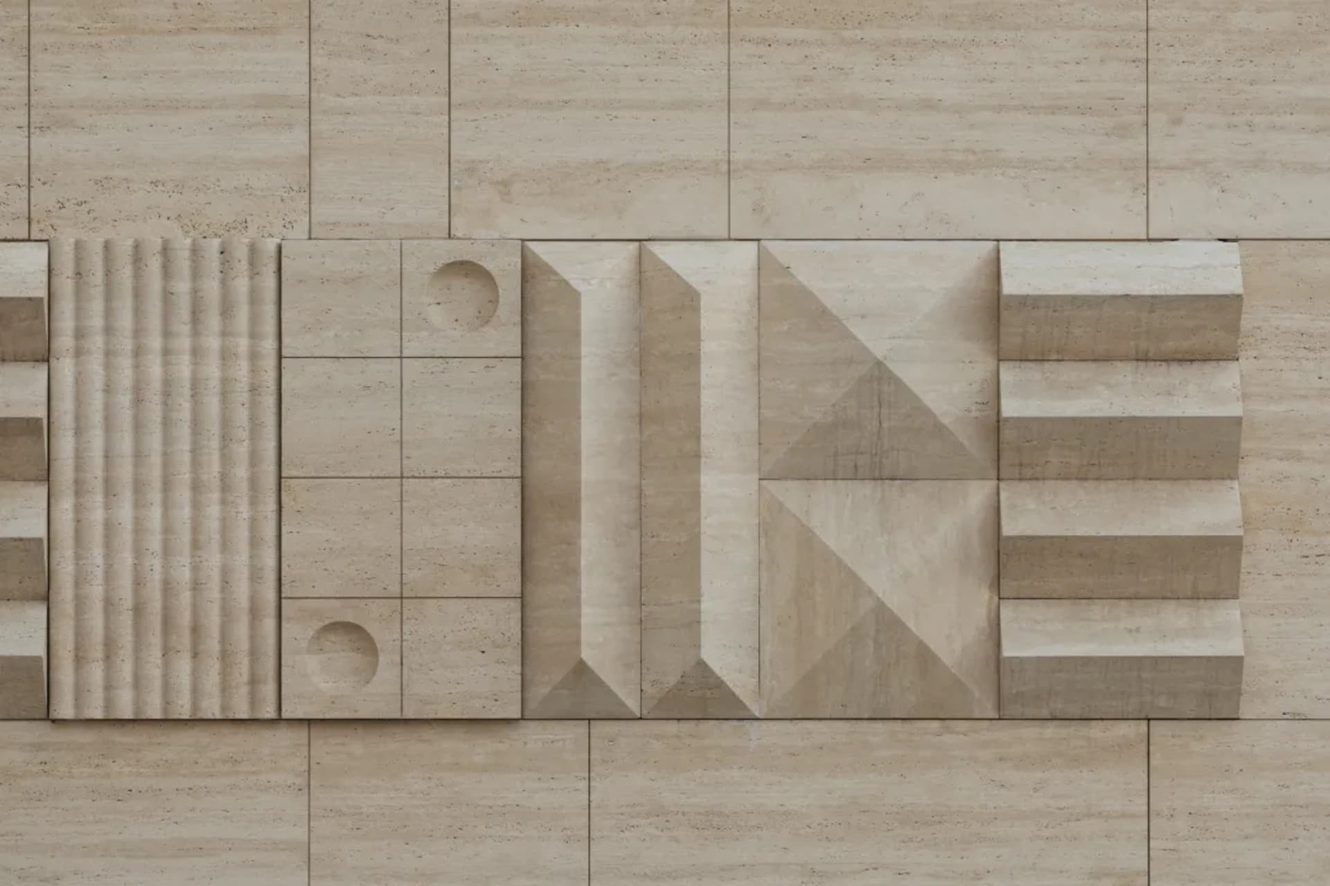 Close-up of a beige travertine stone wall featuring various three-dimensional geometric patterns including fluted columns, circular cutouts, angular pyramids, and stepped reliefs.