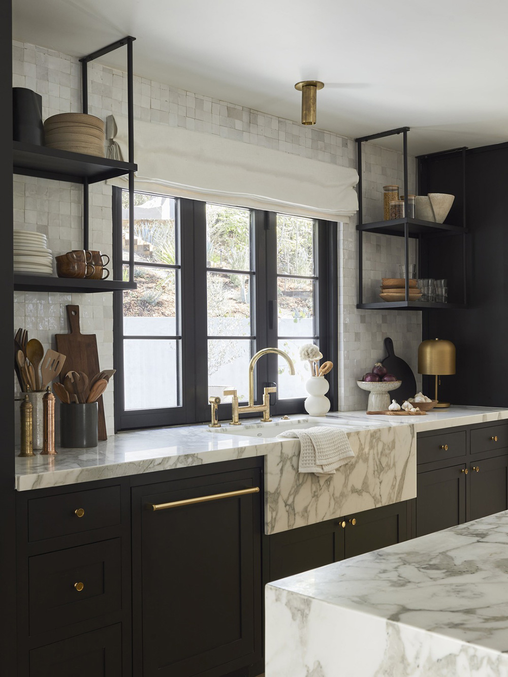 Modern minimalist kitchen with marble counters, brass fixtures, and black accents — illustrating the $8K–$18K remodel bracket for galley kitchens