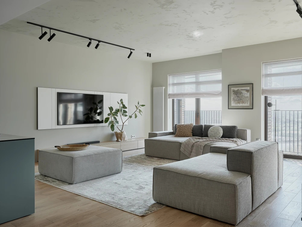 Warm minimalist living room with neutral fabric seating, a low table, and soft natural light.