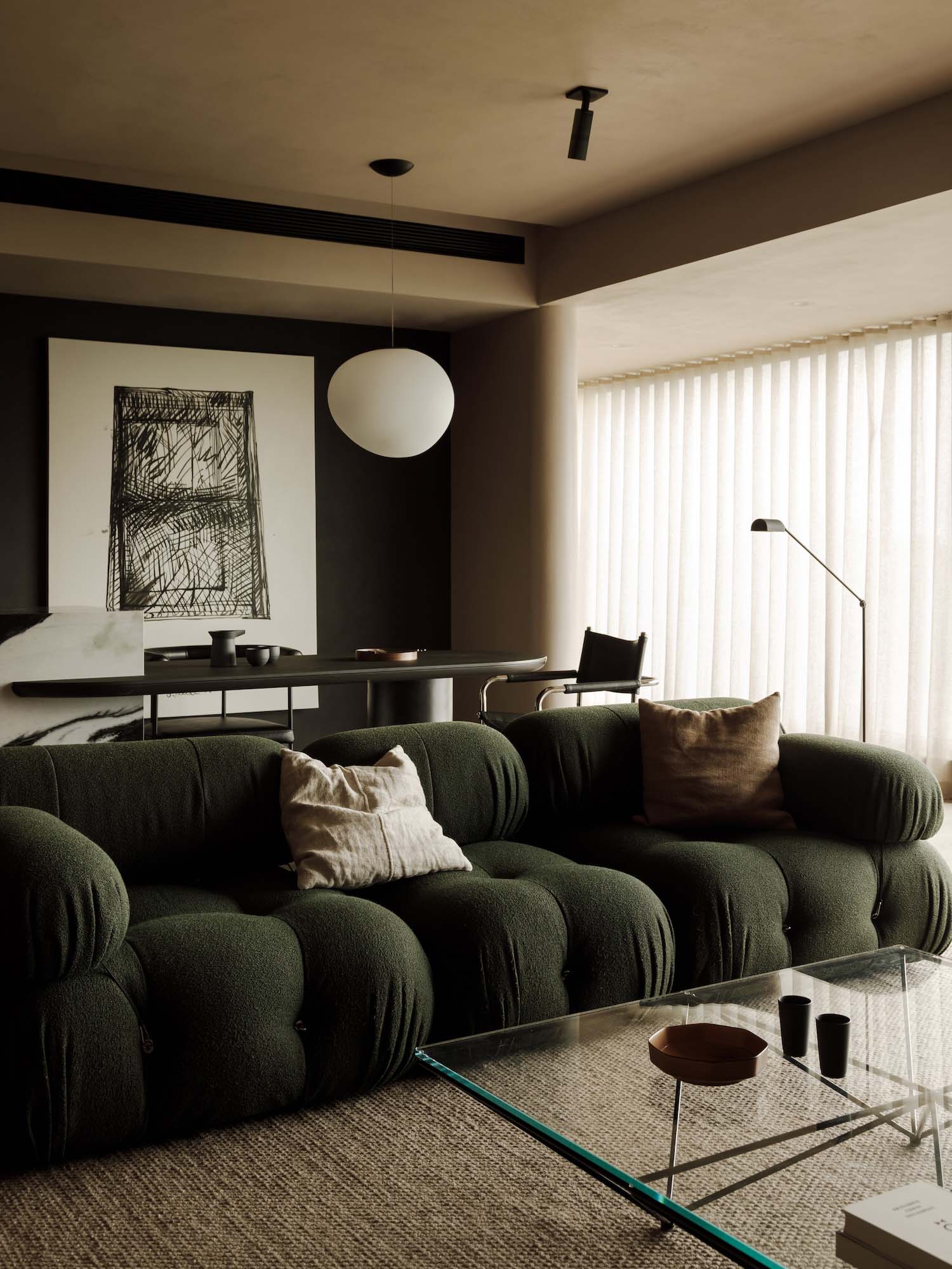Modern living room with dark accent wall, structured sofa, and warm ambient lighting.