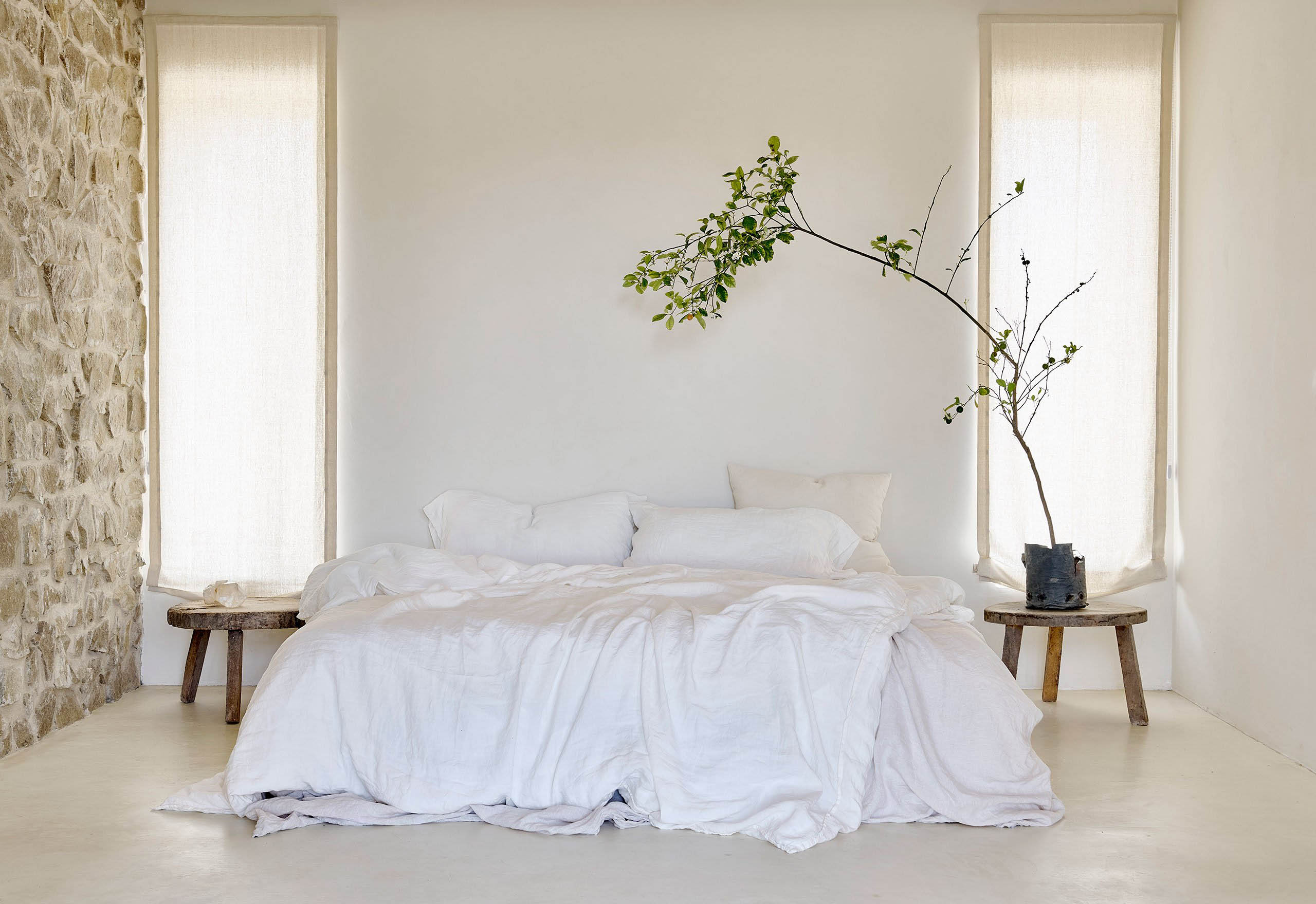 Small japandi bedroom with white cotton bedding, neutral tones, and abundant natural light — a serene minimal setup.