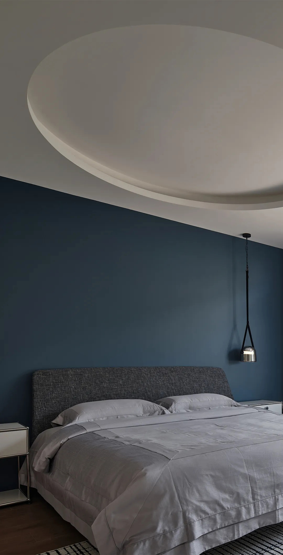 Modern bedroom with cool gray fabric headboard, subtle metal accents, and soft directional lighting in a scandinavian style.