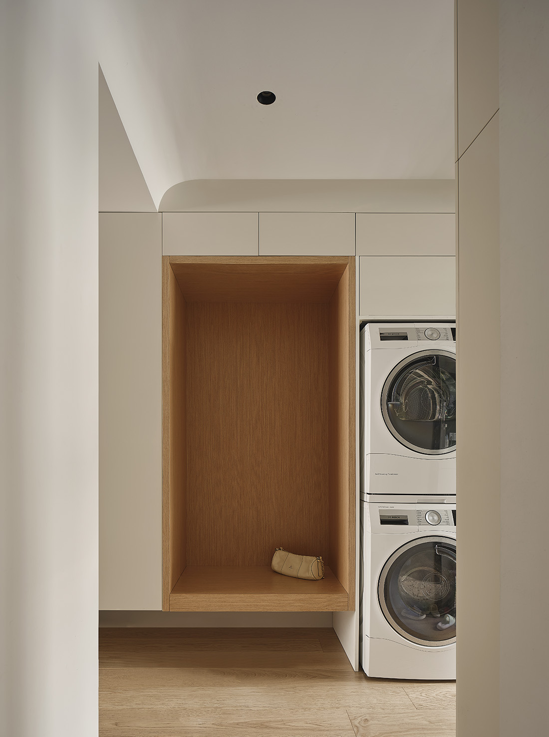 Modern laundry room with wood cabinets, open counter space, and organized utility storage.