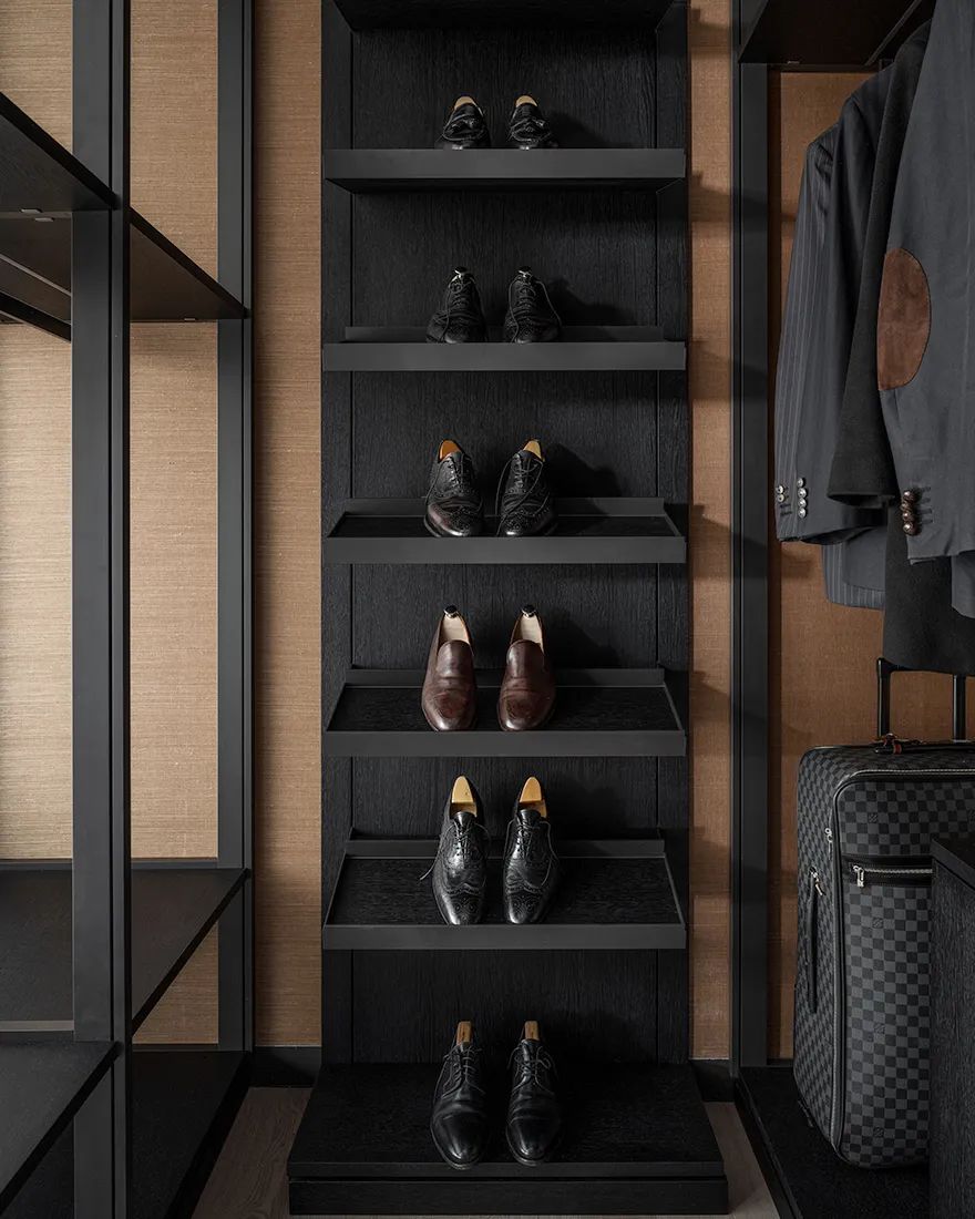 Modern entryway shoe closet with black wood shelving and minimalist storage zones.