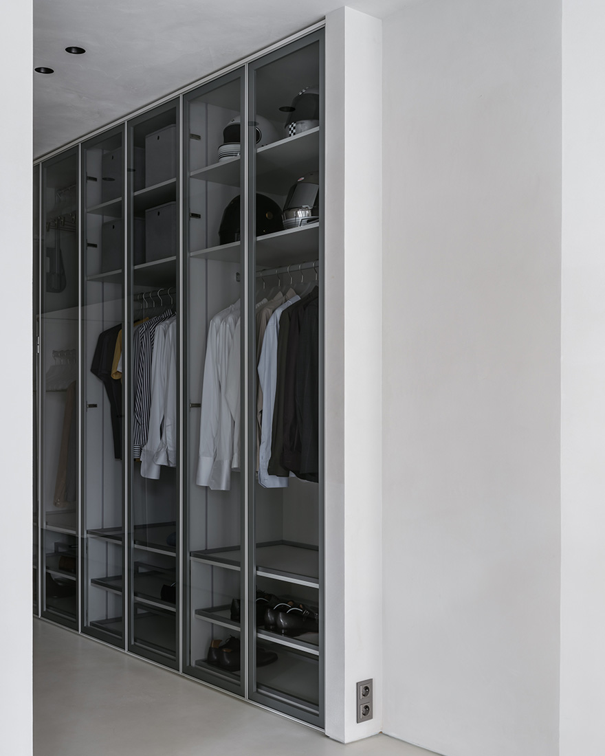 Built-in closet shelving in warm neutral wood, organized into open compartments for clothing storage.
