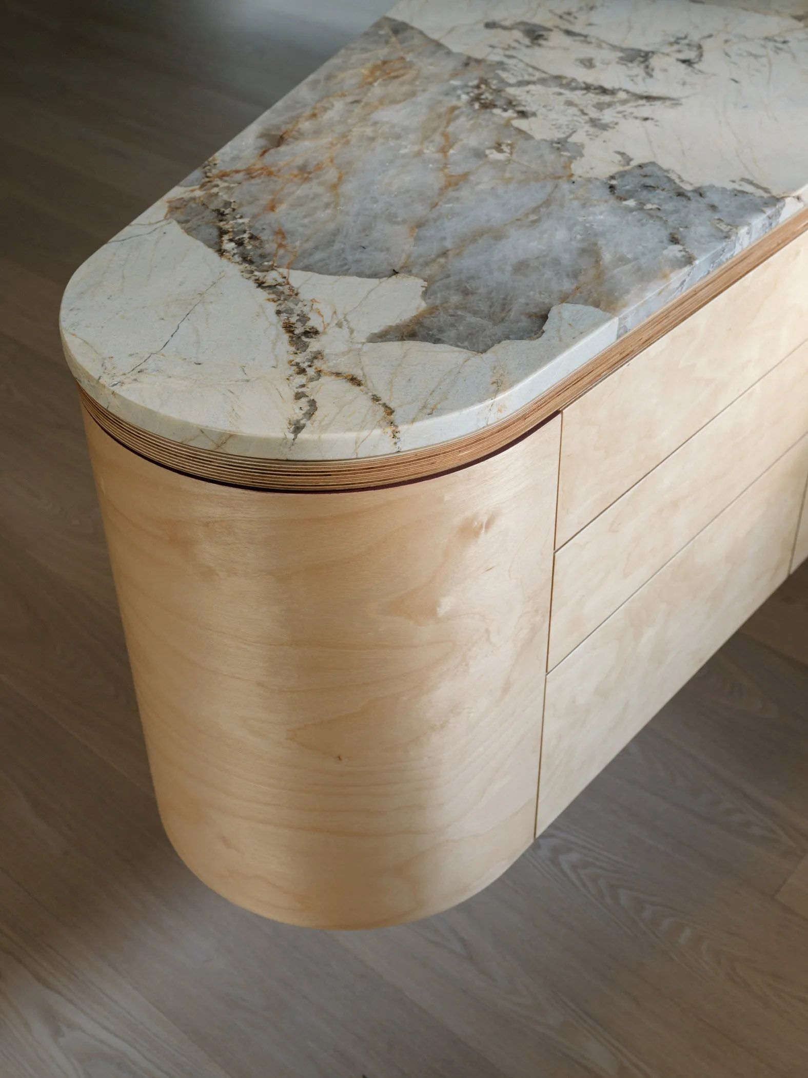 Minimalist kitchen featuring a marble island with veined stone top and warm neutral cabinetry.