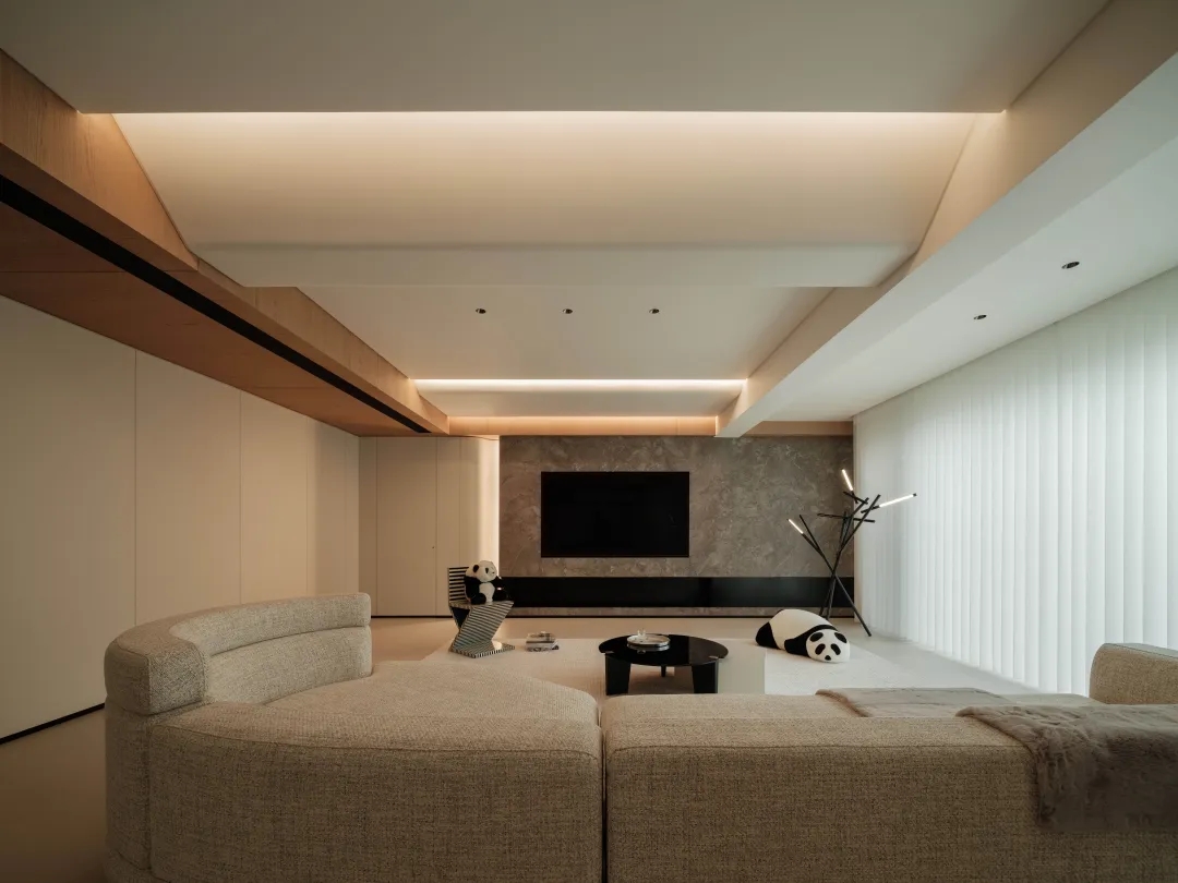 Living room ceiling with warm LED strip cove lighting glowing along wood beams above a neutral sofa.