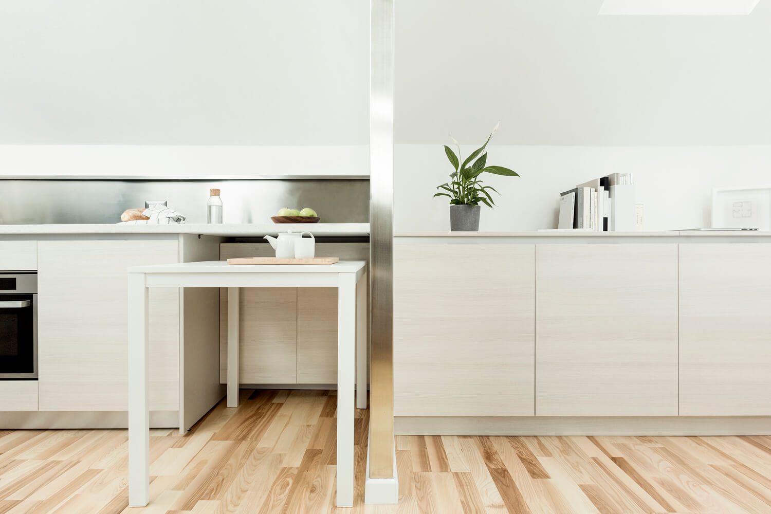 Modern minimalist kitchen with white island table, clean sightlines, and uncluttered countertops.