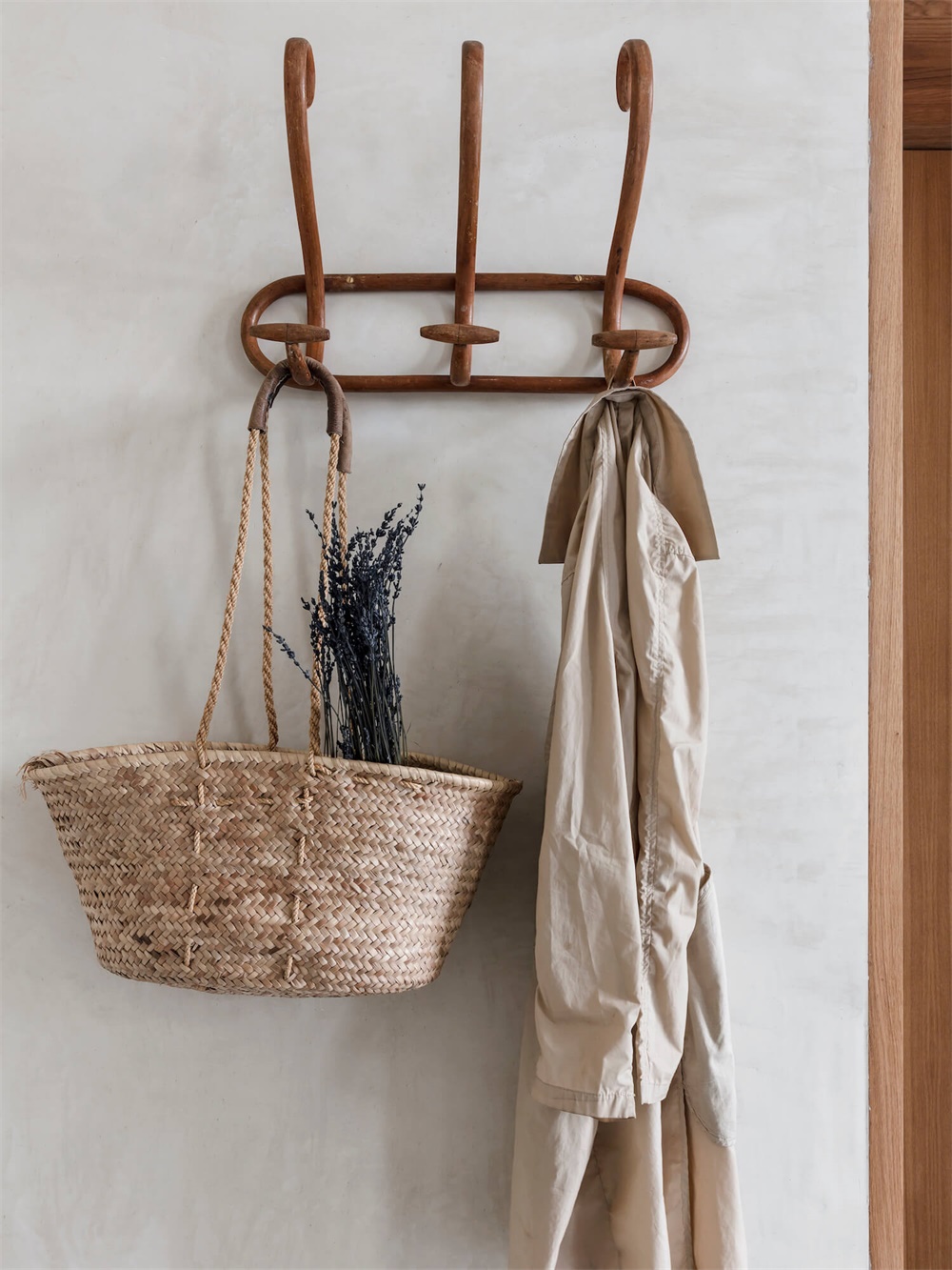 Entryway wall organization with wooden coat hooks, a woven basket, and hanging coats.