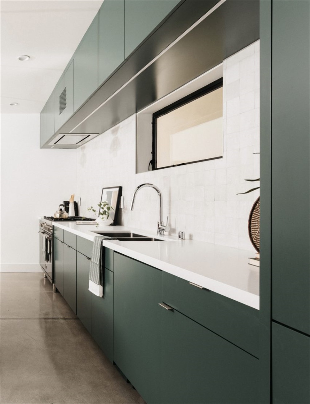 Modern kitchen with dark forest-green lower cabinets and white countertop — illustrating the two-tone color approach designers recommend for 2026 and beyond