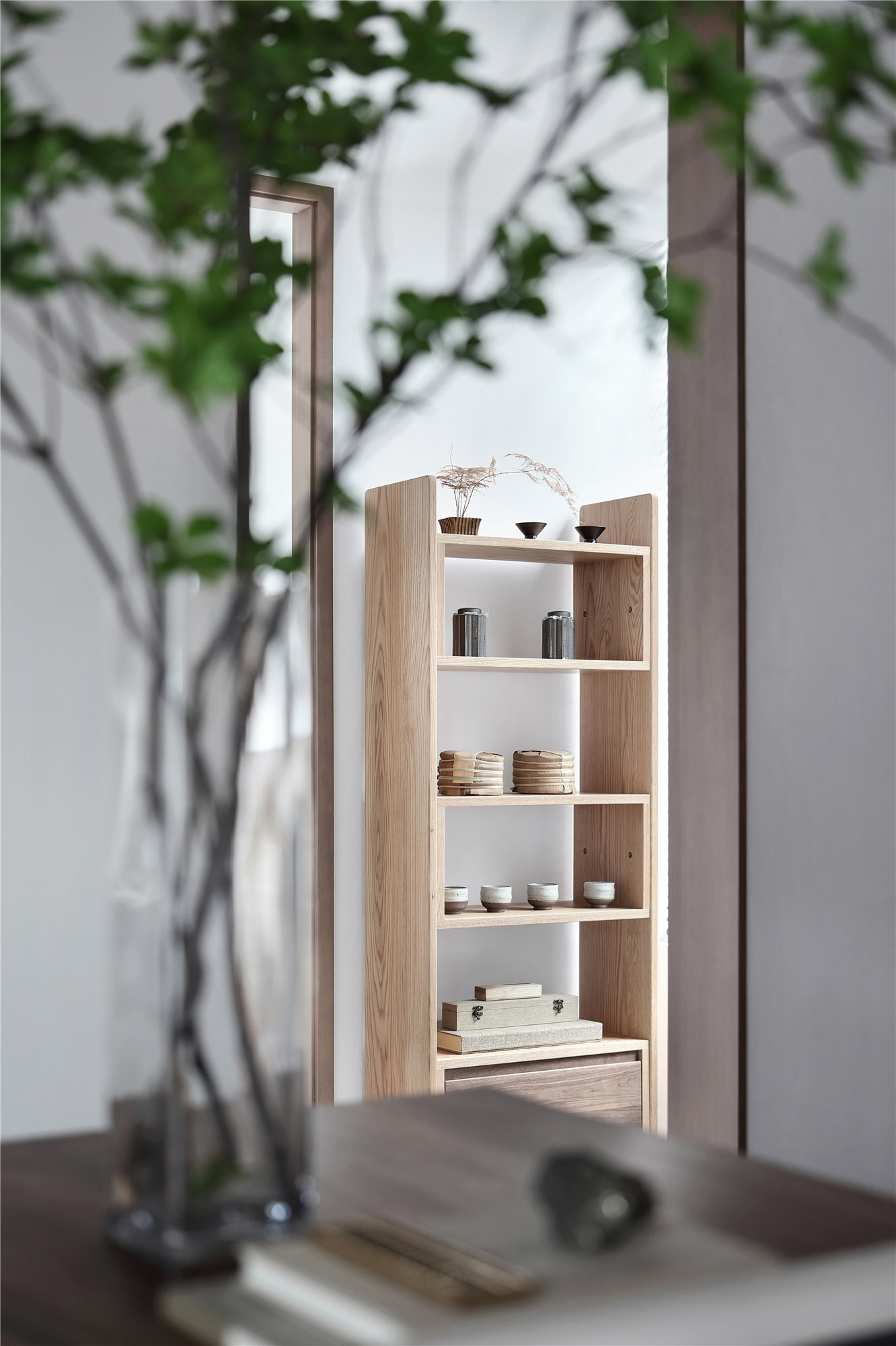 Minimalist interior with open wood shelves acting as a room divider, plants integrated at shelf base.