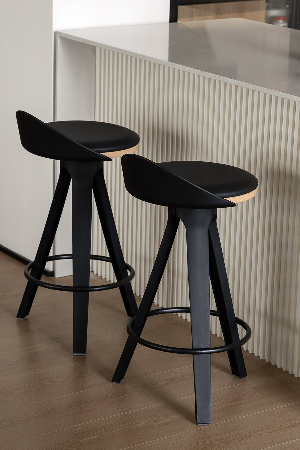 Modern kitchen counter with black industrial bar stools, showing breakfast seating at an island.