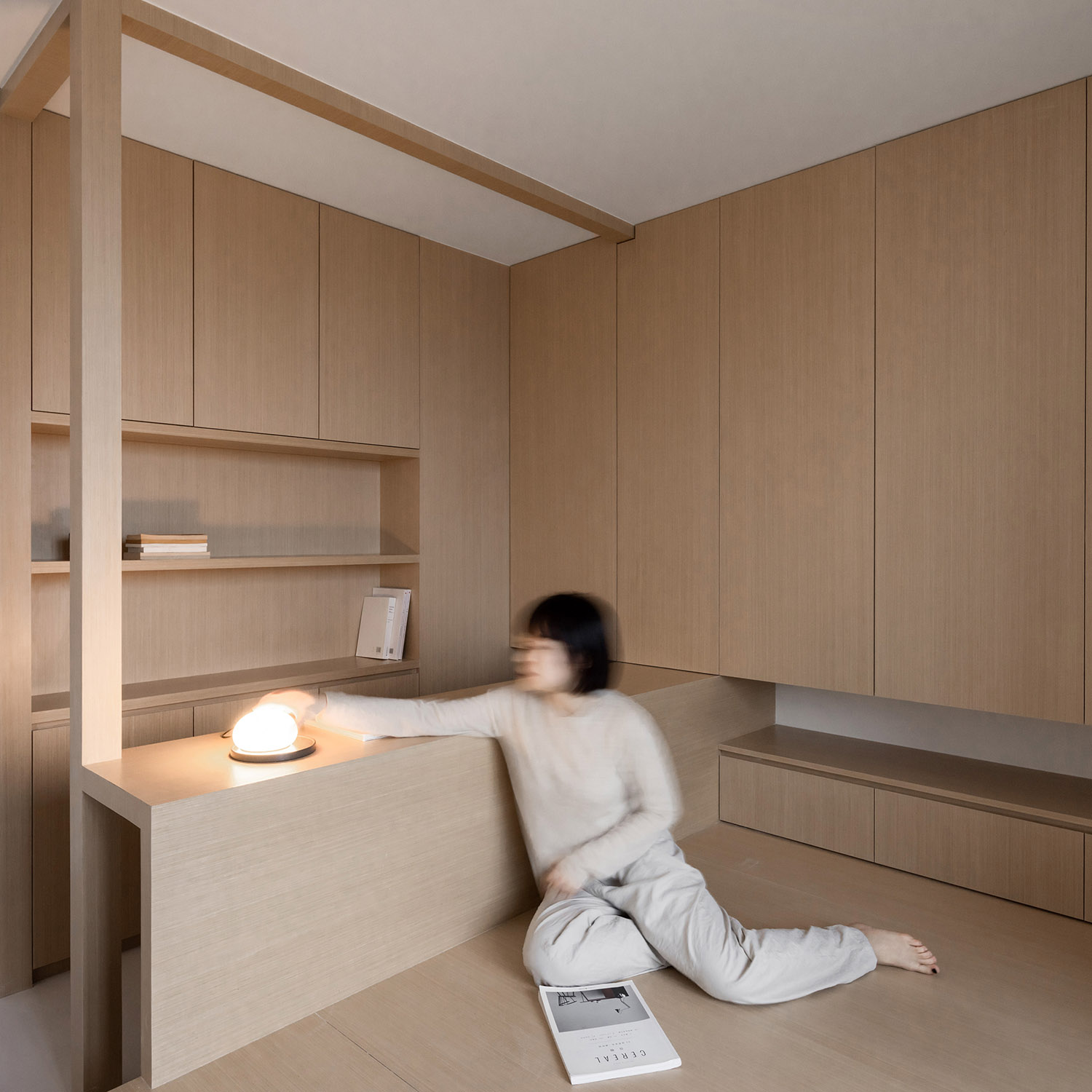 Japandi small apartment interior with warm wood walls, built-in storage, and minimalist seating.