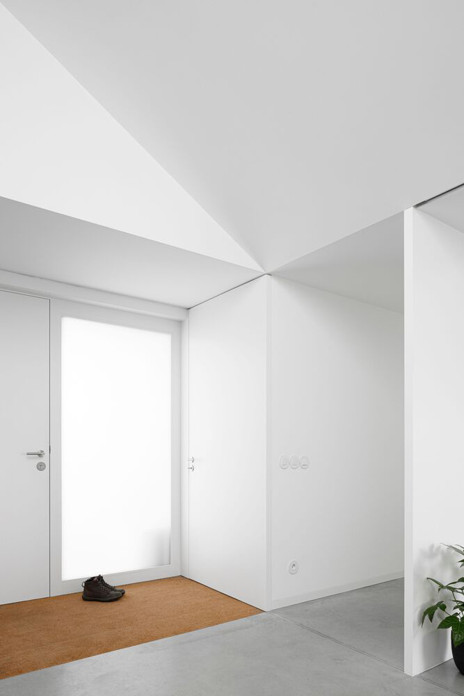 Clean white minimalist interior with subtle recessed shadow lines at wall junctions, offering a frameless look without full molding removal.
