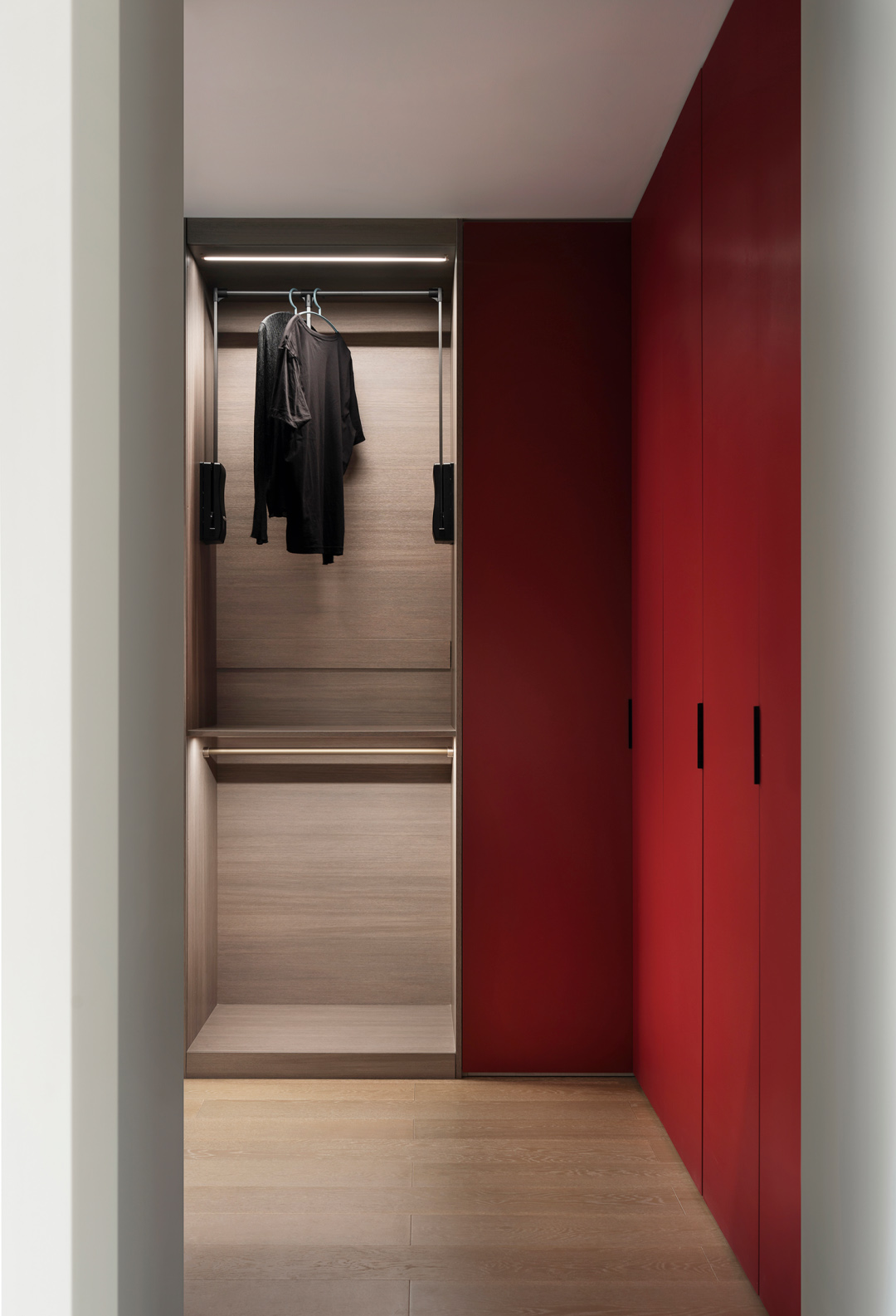 Modern minimalist walk-in closet with warm wood tones and an open, uncluttered layout.