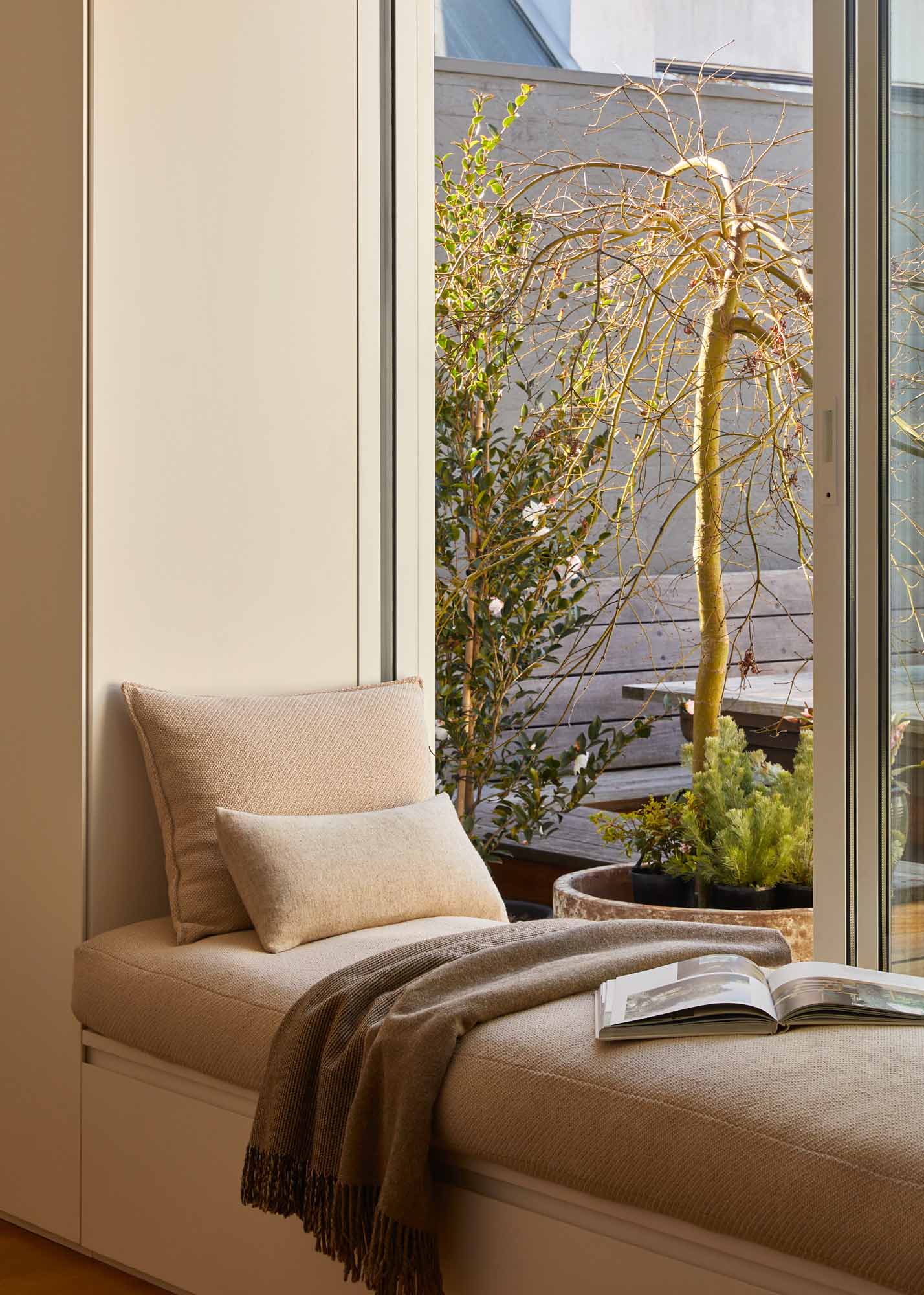 Cozy corner with a soft sofa positioned by a window with an outdoor view, ideal for a compact reading nook.