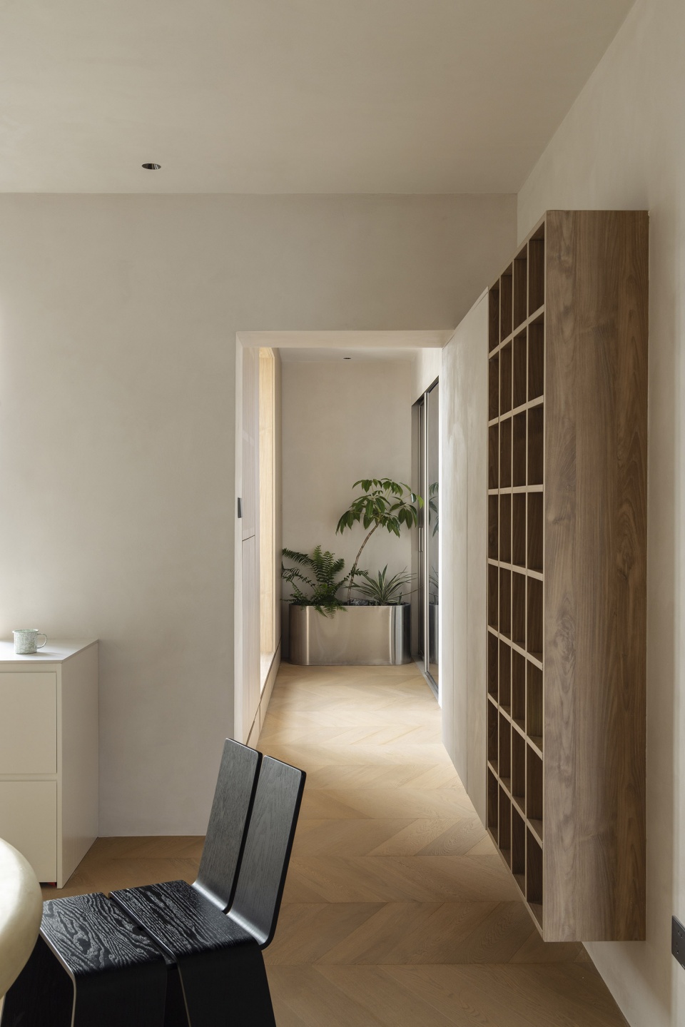 Modern minimalist corridor with wood details and a narrow circulation path through the entry.