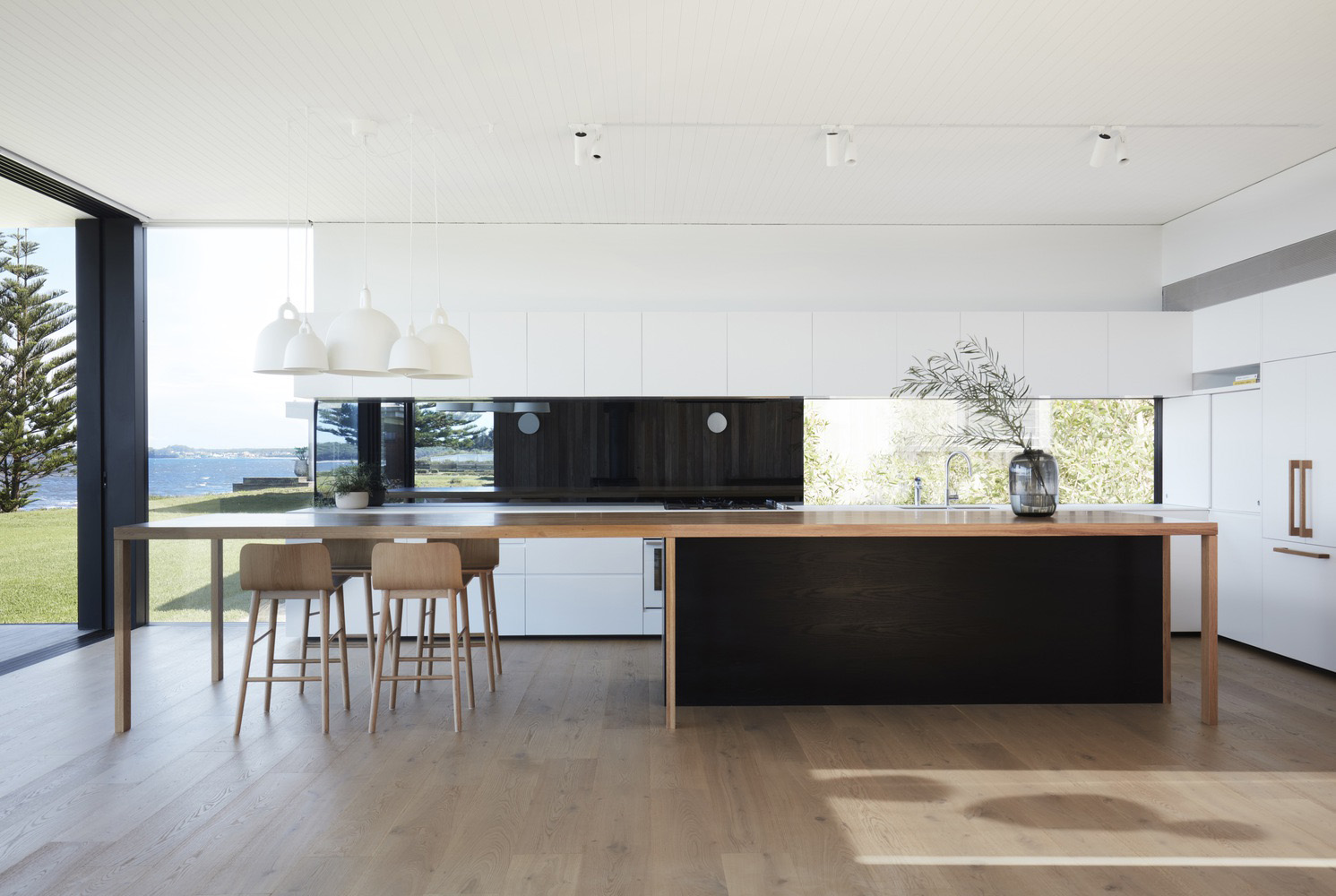Modern minimalist kitchen with open layout, clean lines, light cabinetry, and stone countertops.
