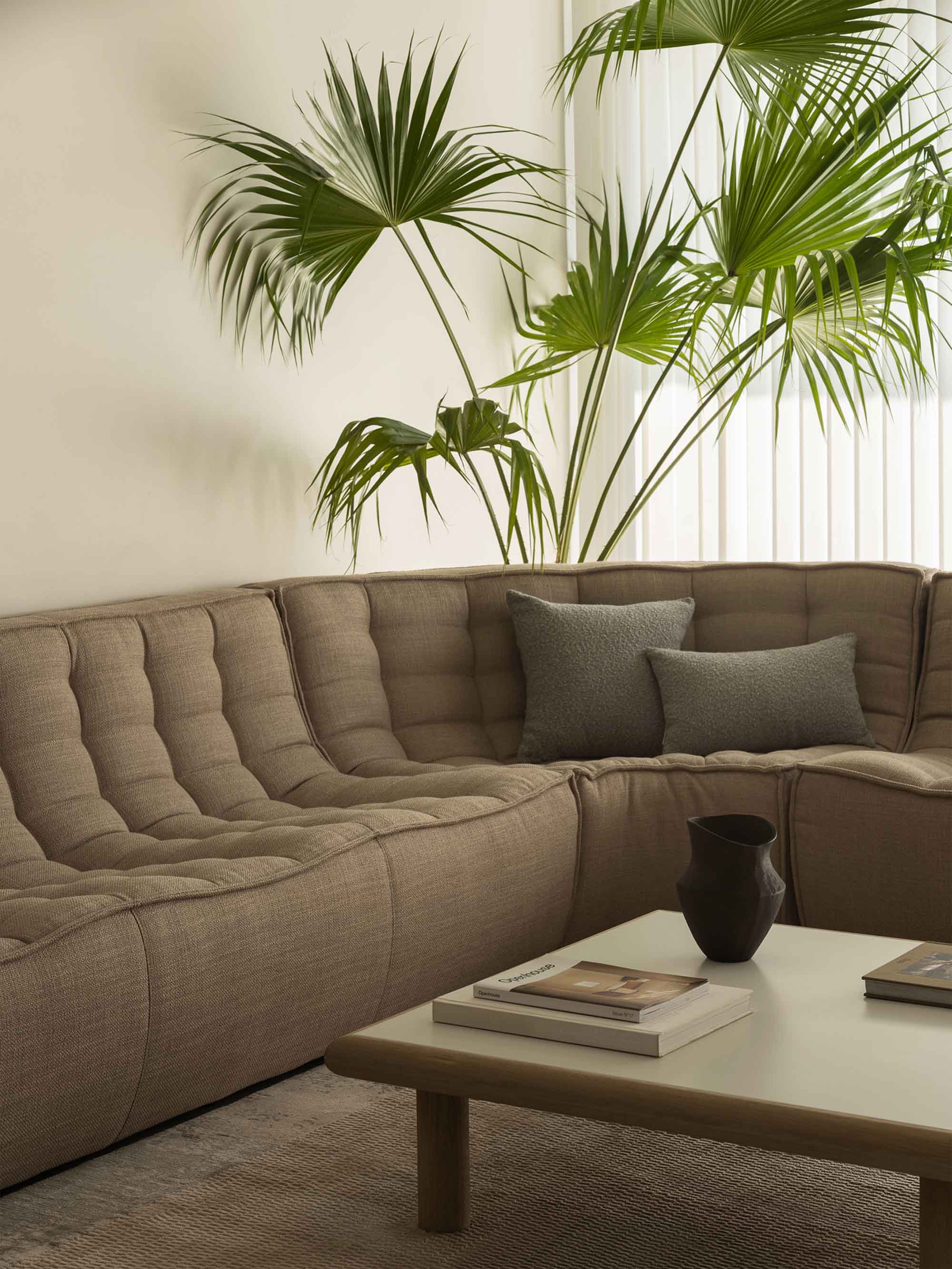 Modern living room with fabric sectional sofa in warm tones, earthy palette, and soft furnishings.