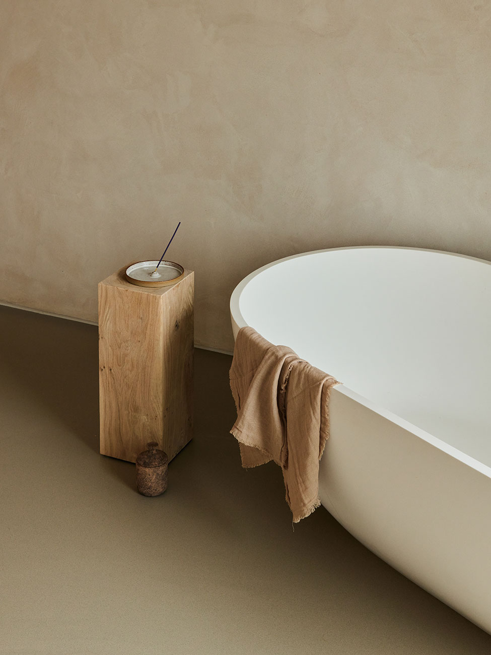 Minimalist hotel bathroom with large-format warm porcelain tile walls and floors, soft neutral tones, and spa-style vanity lighting.