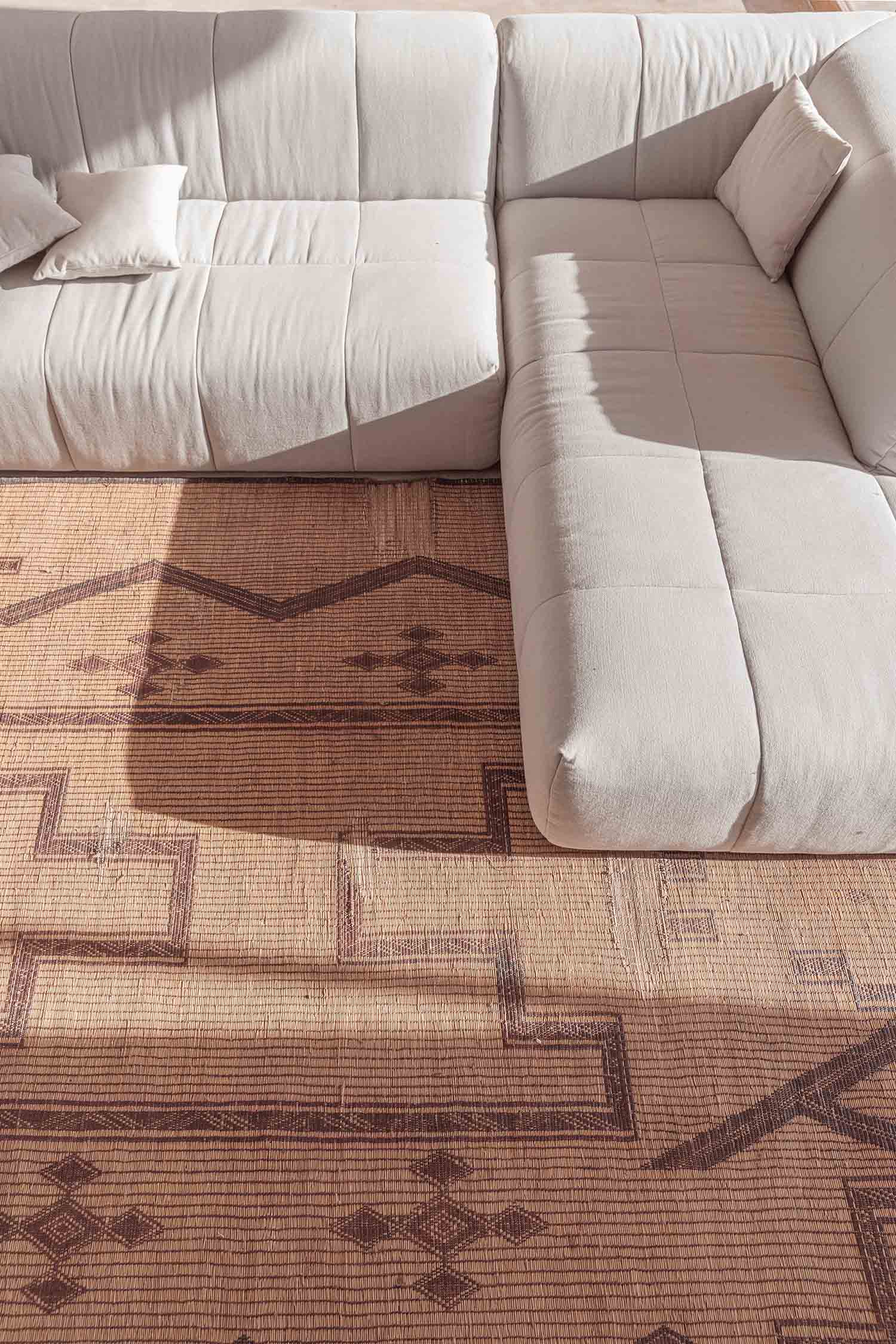 Warm neutral living space with a patterned wool runner rug over tiled flooring.